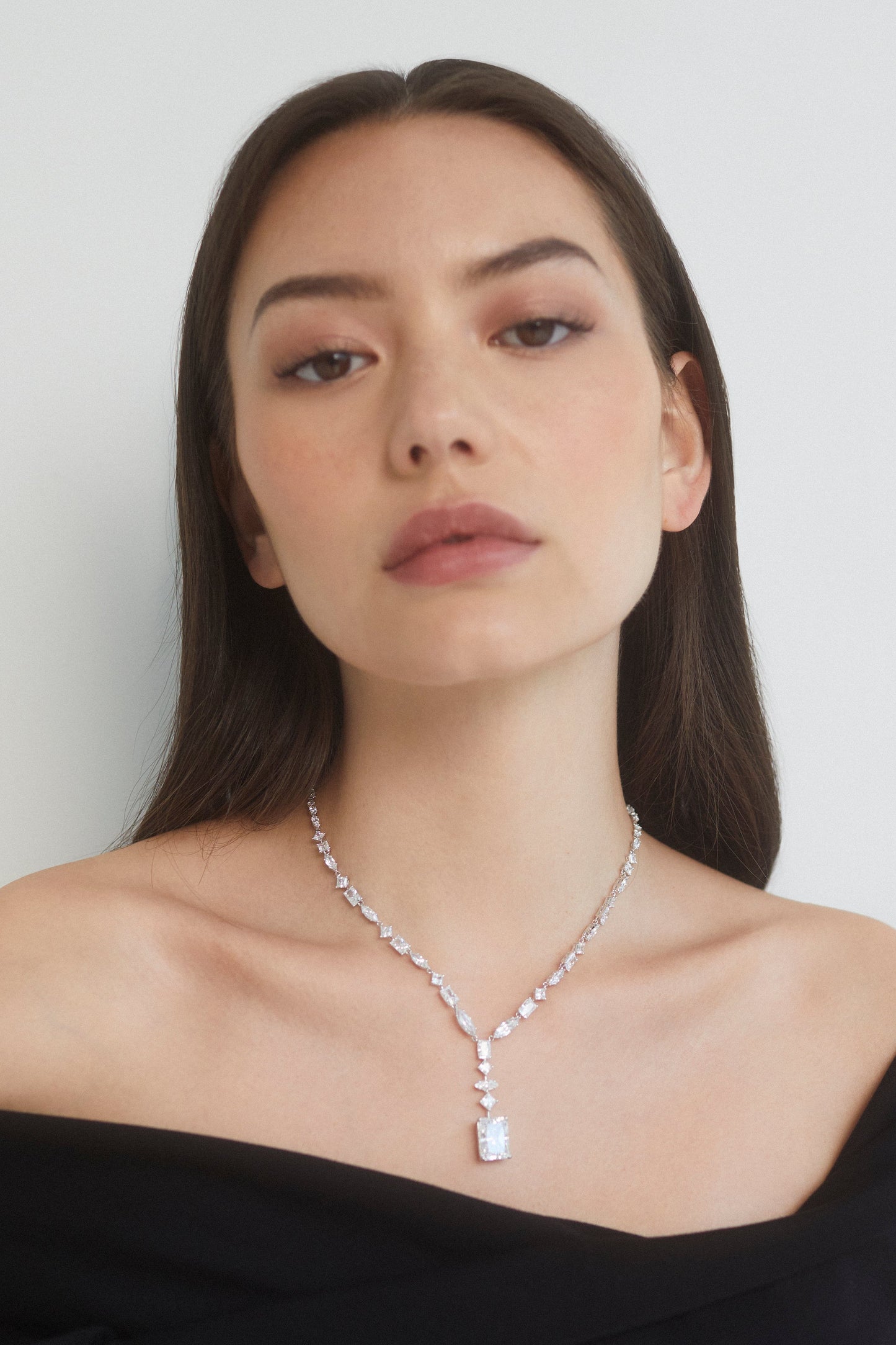CLOSE UP IMAGE OF MODEL WEARING THE RARE JEWELS MIXED-CUT CZ STATEMENT Y NECKLACE IN RHODIUM PLATING WITH A BLACK OFF THE SHOULDER TOP.