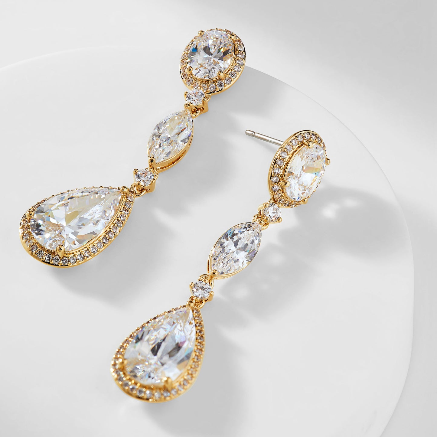CZ PEAR AND OVAL DROP EARRINGS IN GOLD PLATING WITH ONE EARRING TURNED ON ITS SIDE TO SHOW THE POST.