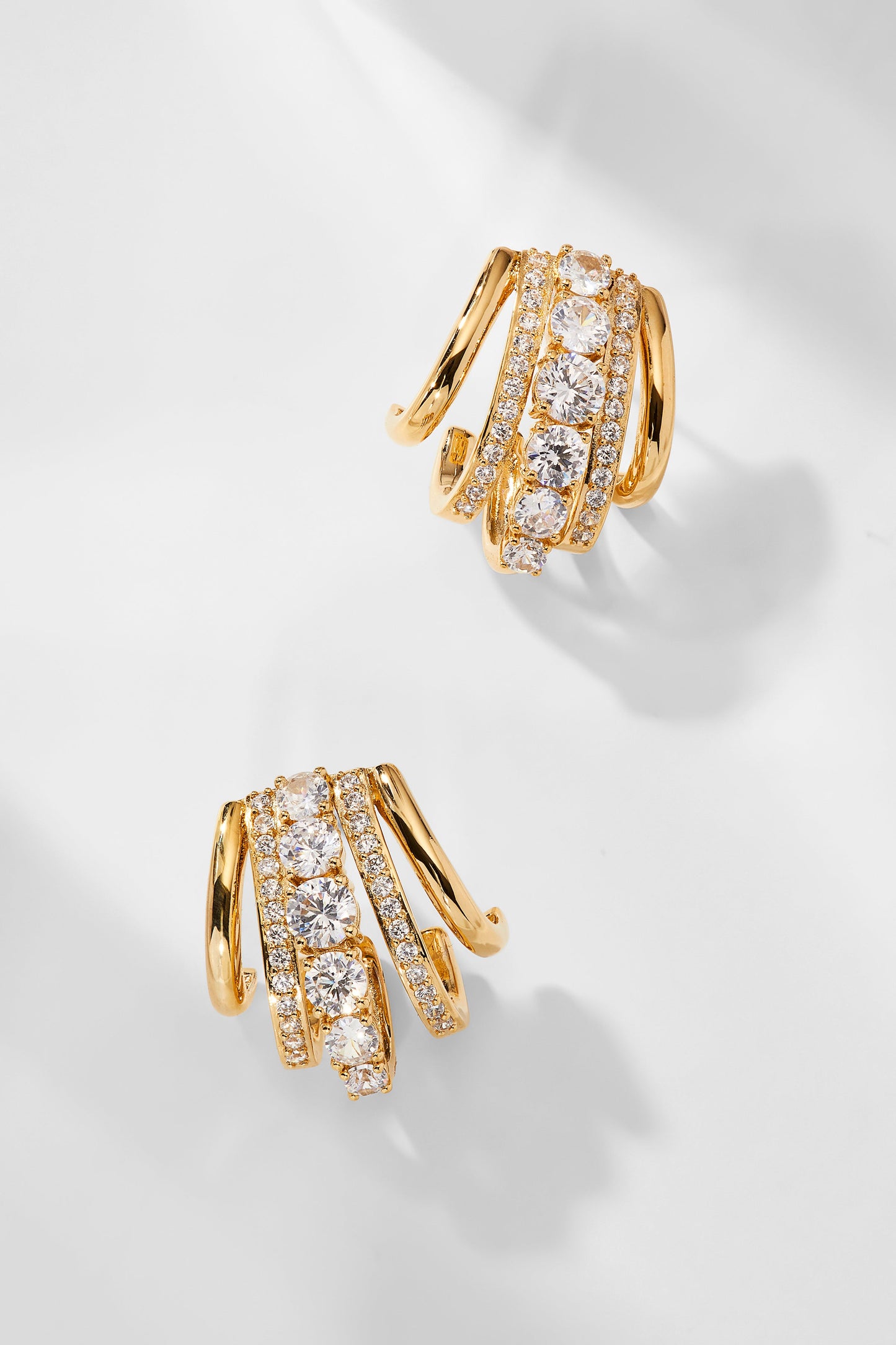 CLEO J HOOP CZ HUGGIE EARRINGS IN GOLD PLATING.