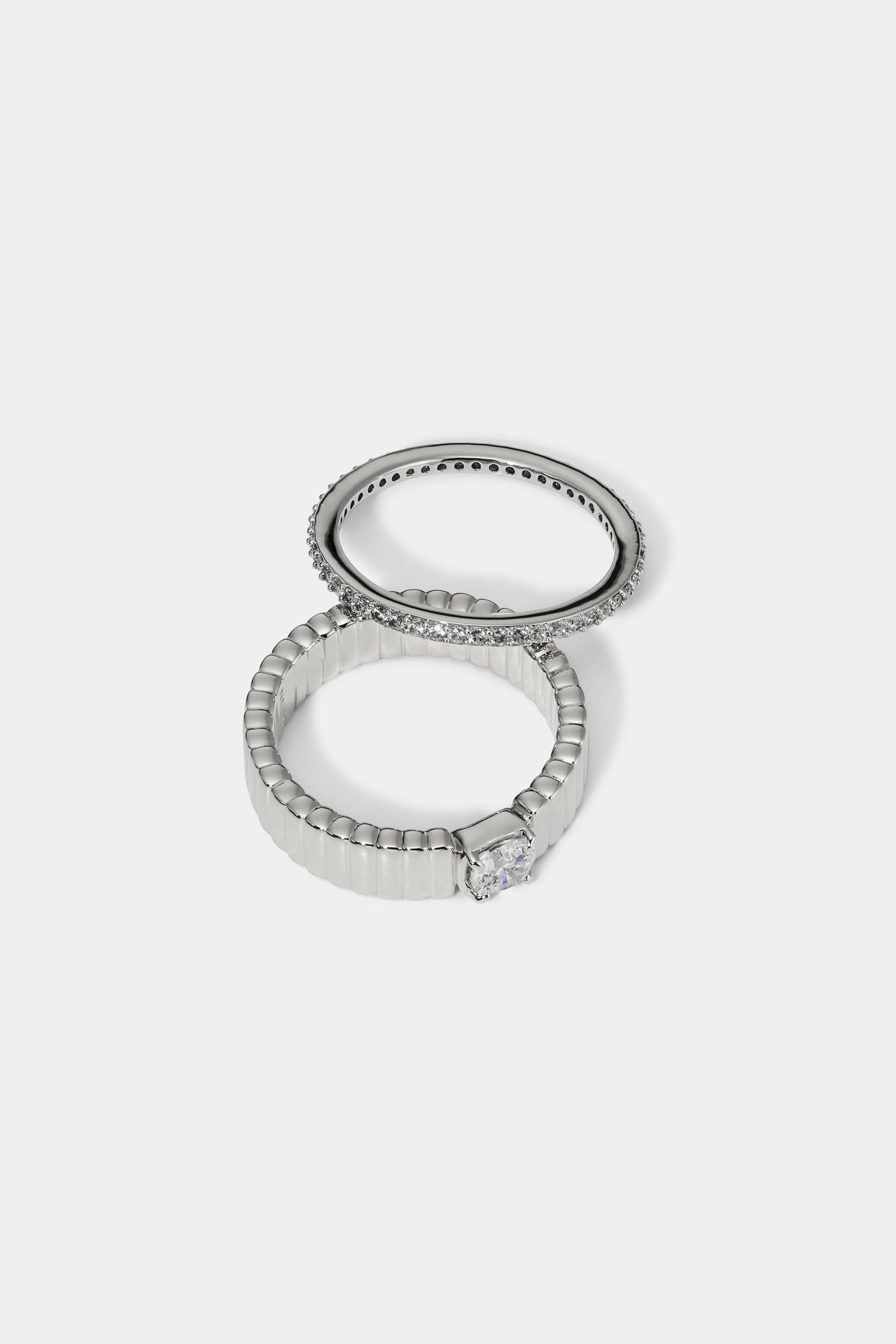 DELANCEY SOLITAIRE RING SET IN RHODIUM PLATING, SLIGHTLY SEPARATED TO SHOW TWO SEPARATE RINGS