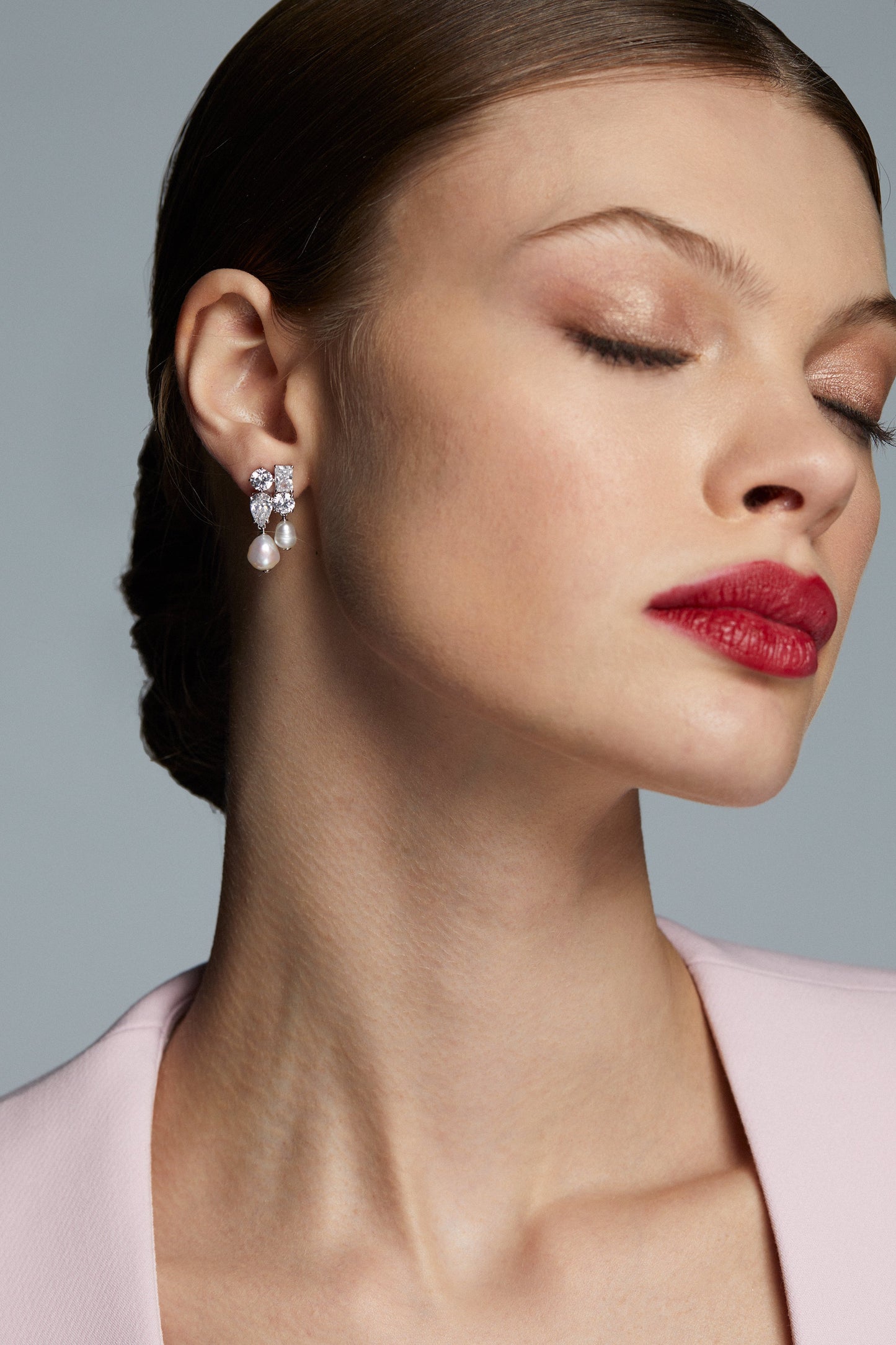 MODEL WEARING LONDON CLUSTER CZ PEARL DROP EARRINGS. HER EYES ARE CLOSED, HAIR IN A SLICK BACK BUN, AND RED LIPSTICK ON. 