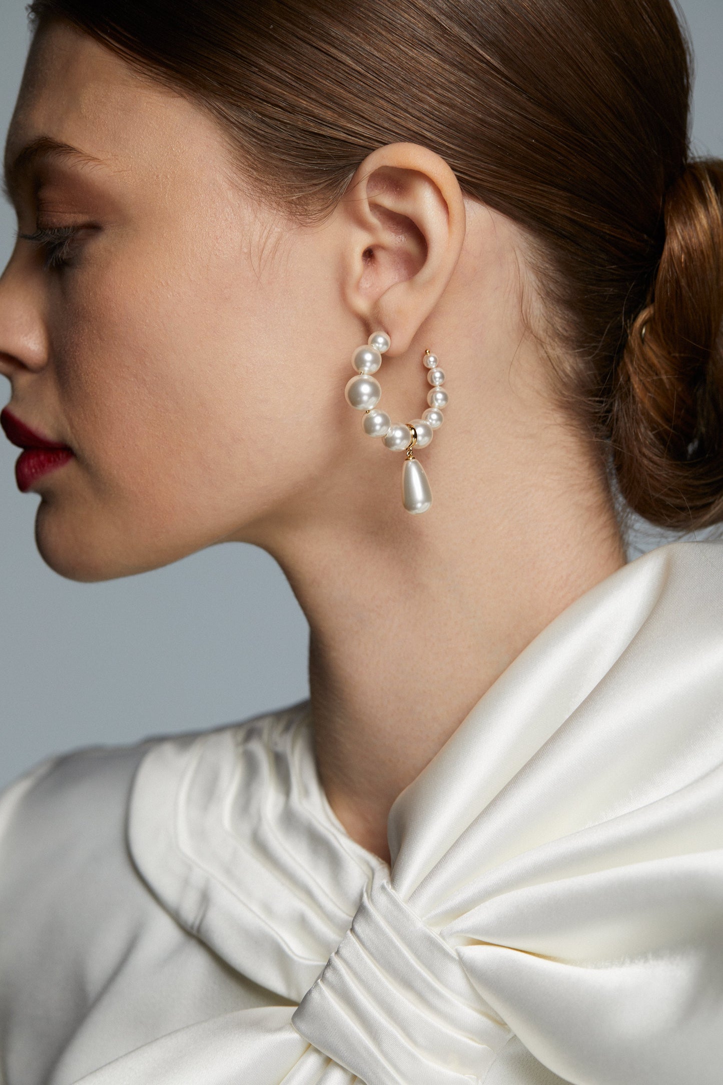 MODEL WEARING LONDON PEARL DROP C HOOP EARRINGS - SIDE PROFILE SHOT SHOWING A SIDE ANGLE OF THE HOOPS. 