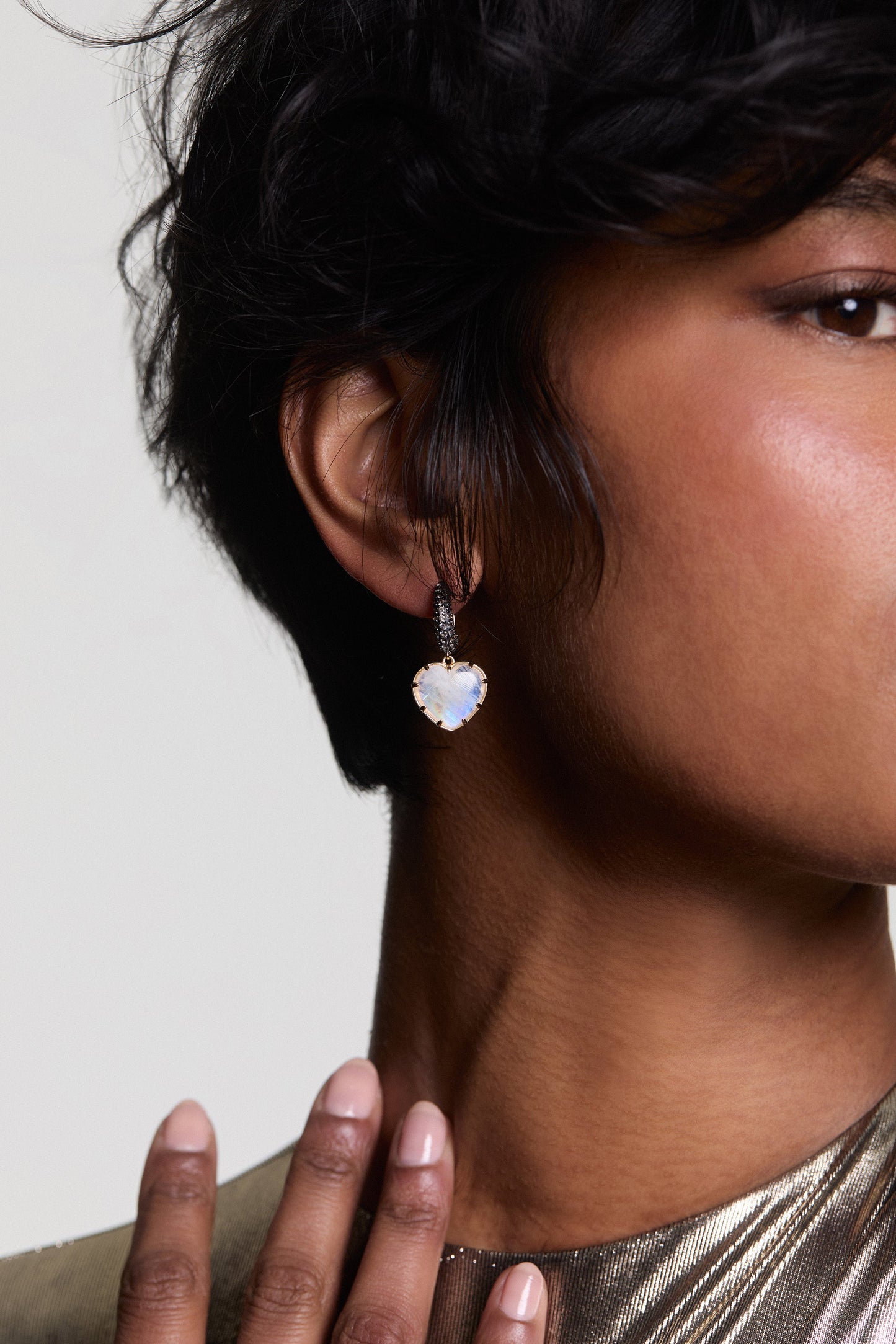 CLOSE UP OF A MODEL’S EAR AS SHE WEARS A GOLD METALLIC TOP AND THE AU NATUREL HEART DROP EARRINGS