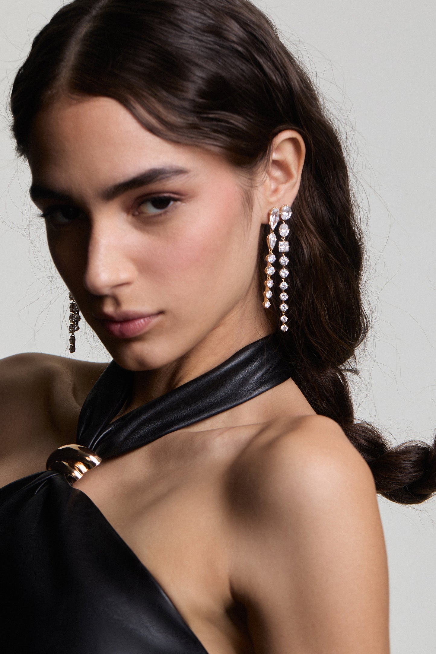 A MODEL LEANING BACK AND LOOKING AT THE CAMERA, HER HAIR BRAIDED AND TUCKED BEHIND HER EAR, WEARING LUCIA DOUBLE LINEAR EARRINGS WITH A BLACK TOP