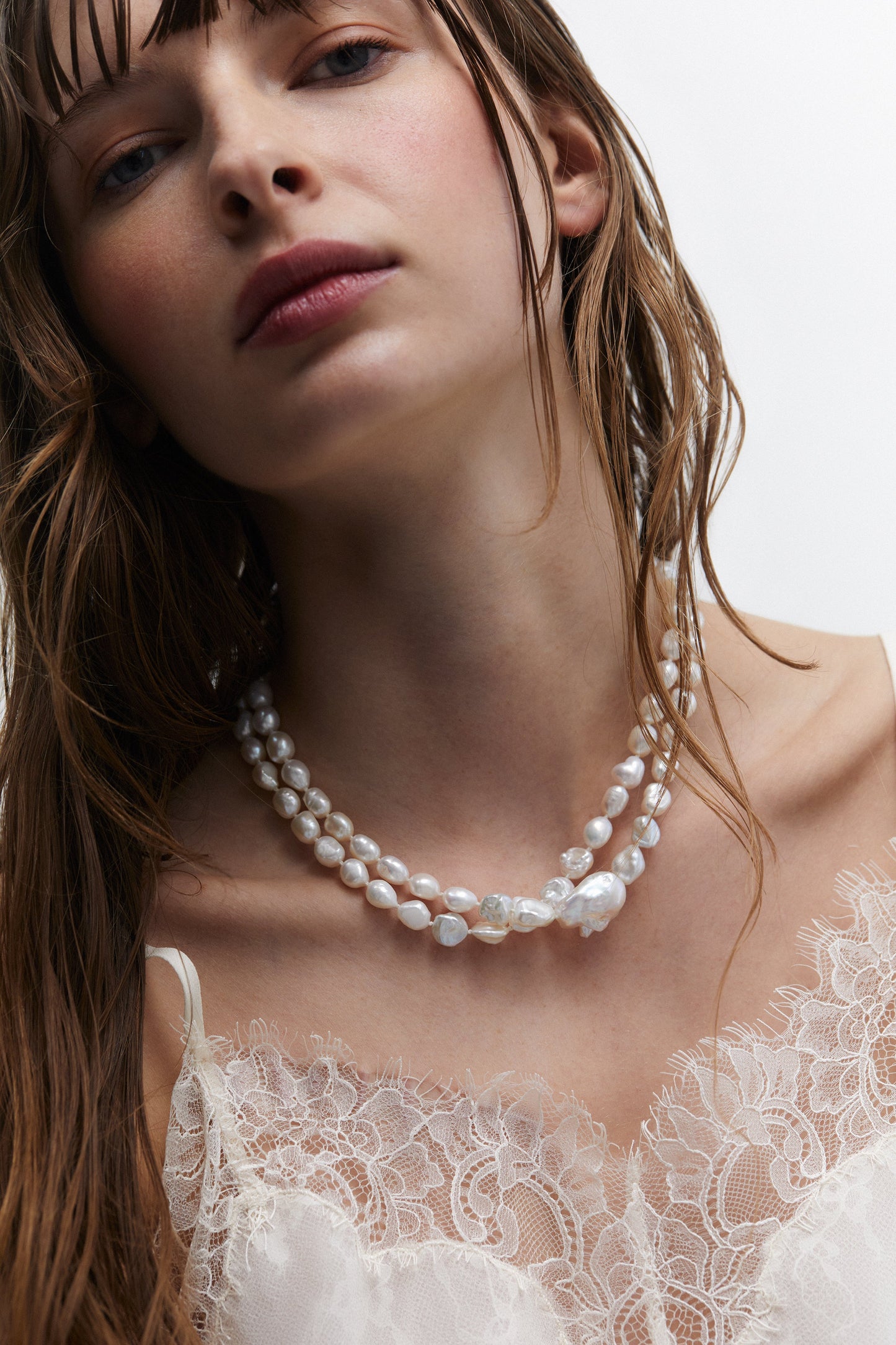MODEL WEARING MADRID FRESHWATER PEARL DOUBLE STRAND NECKLACE WITH A WHITE LACE TOP.