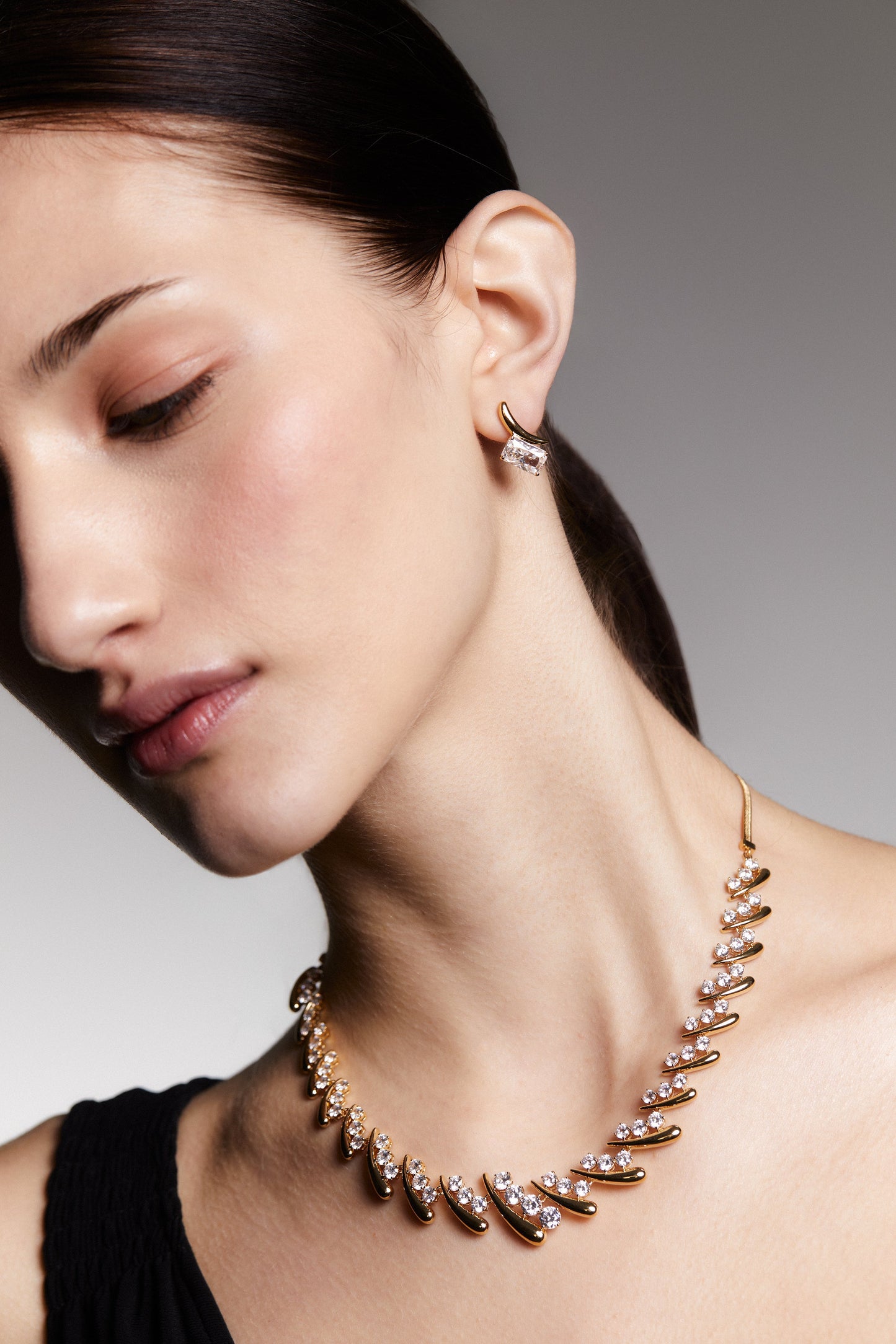 Model wearing Emerald cut cz stone and polished metal stud earrings with a coordinating necklace.  Her head is tilted to the side.
