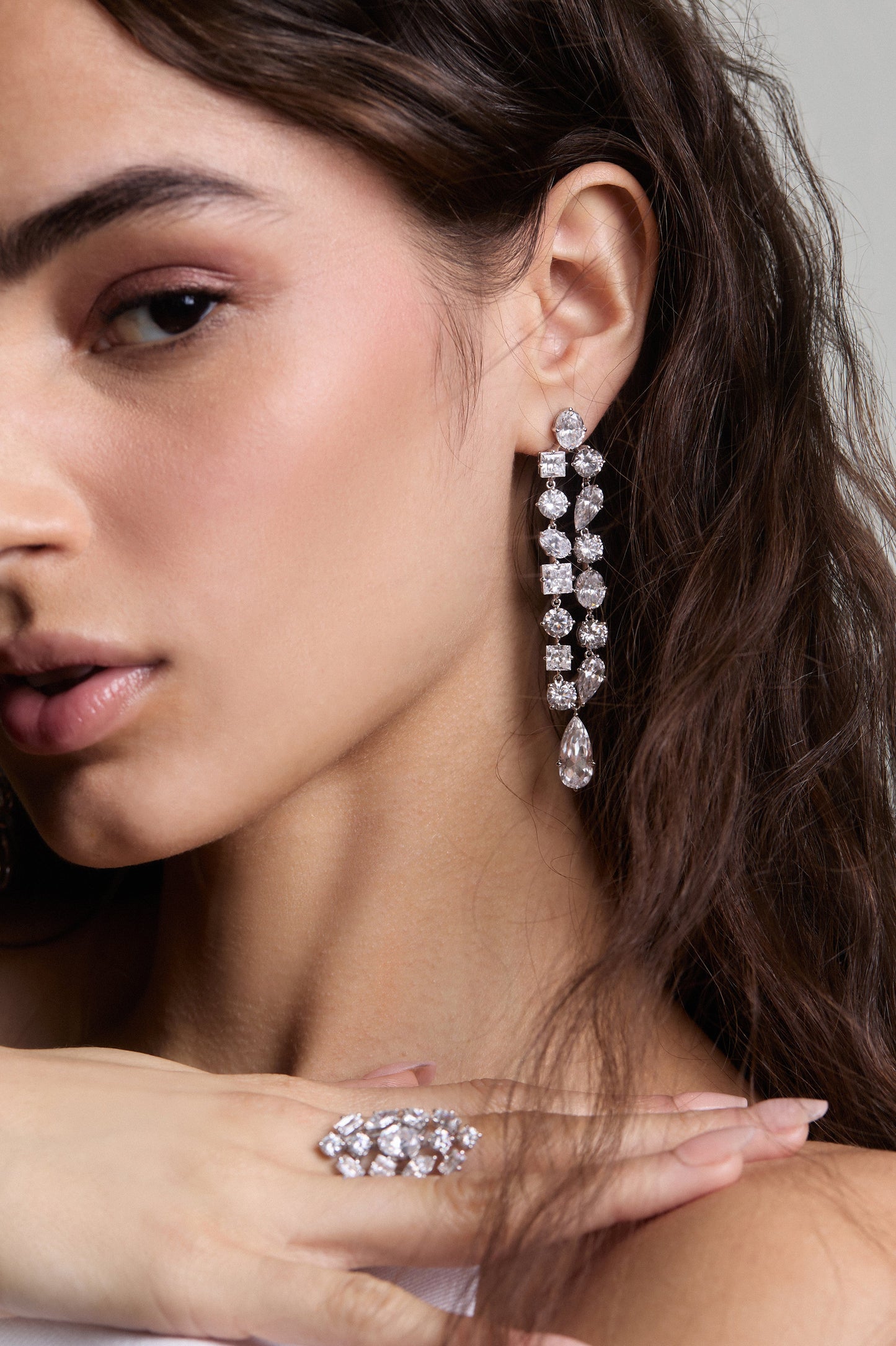 CLOSE UP OF HALF OF A MODEL’S FACE, WEARING THE RIVIERA DOUBLE LINEAR EARRINGS AND HER HAND PLACED ON HER OPPOSITE SHOULDER