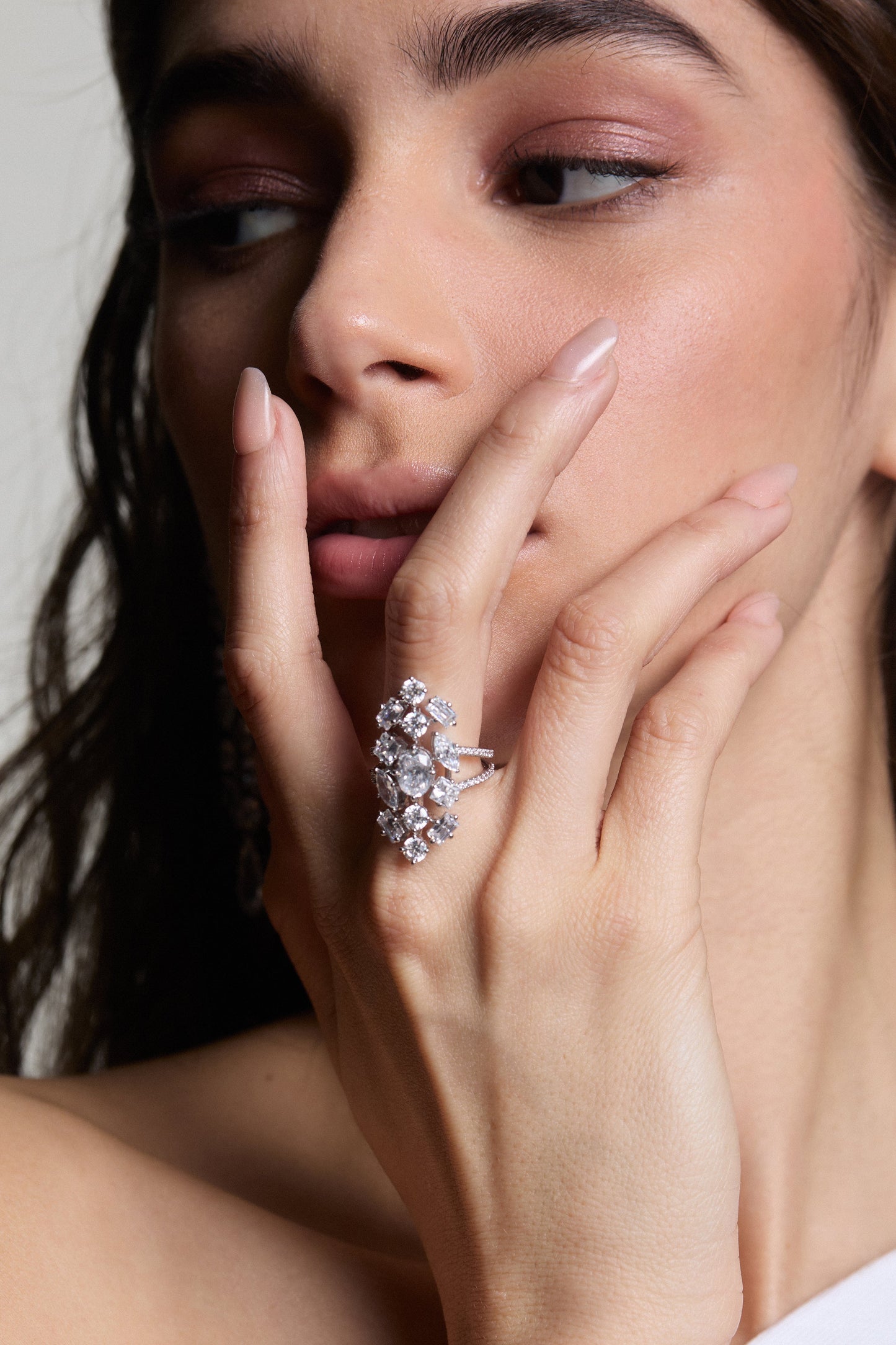 CLOSE UP OF A MODEL WITH HER HAND ON HER FACE WEARING THE RIVIERA SHIELD RING. 