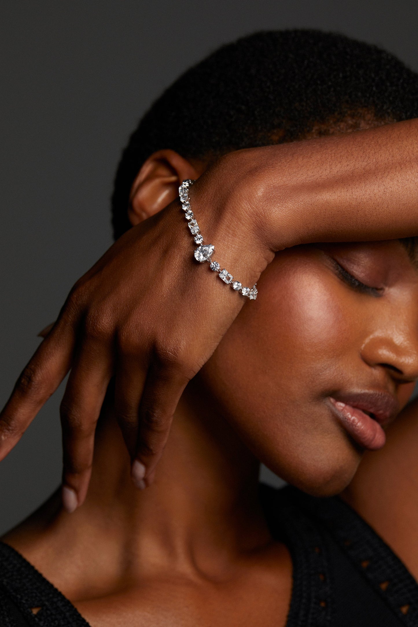 MODEL WEARING EVERLEIGH LINE BRACELET. HER EYES ARE CLOSED AND SHE HAS HER WRIST LIFTED UP TO HER FACE. 