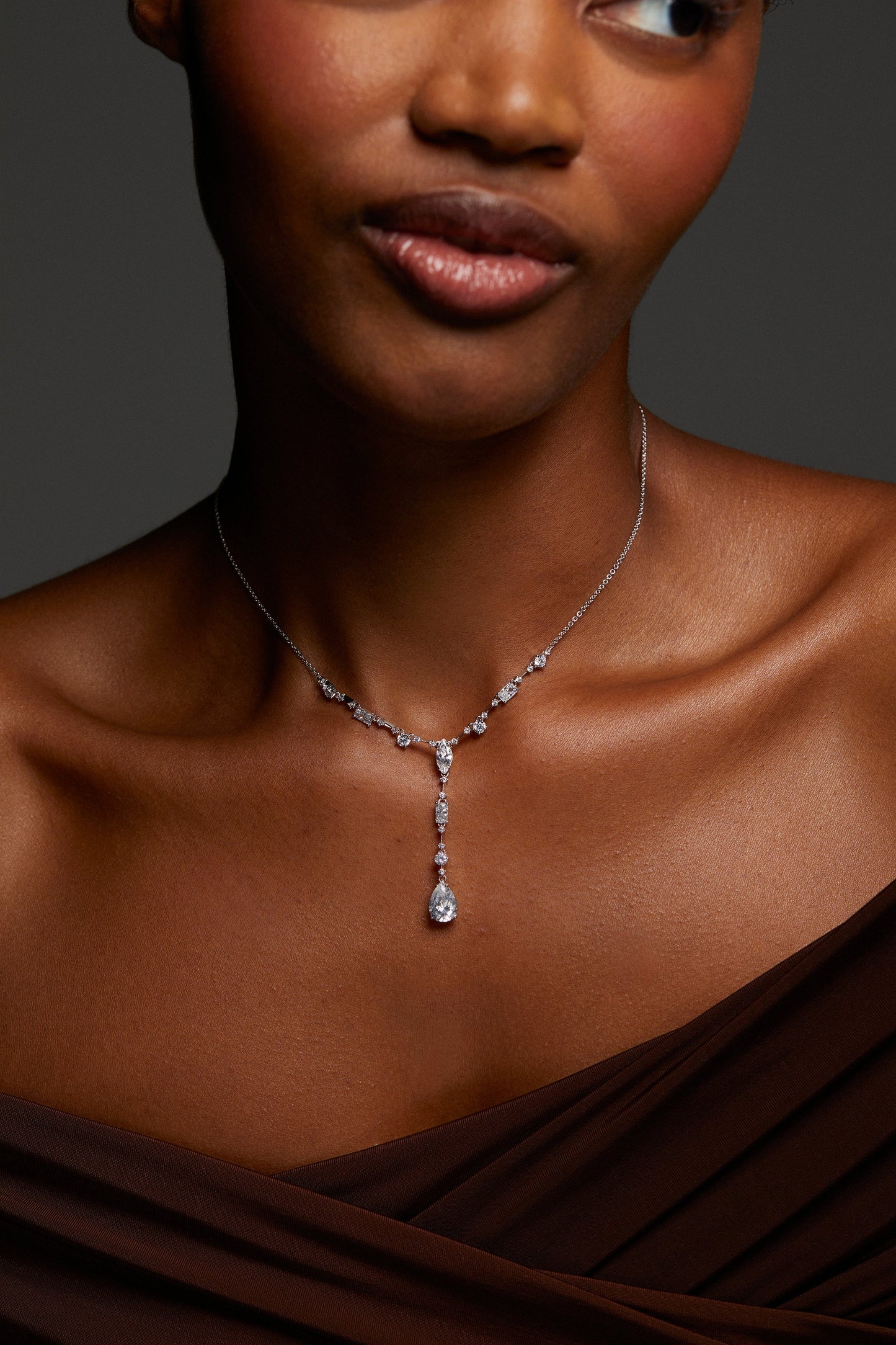CLOSE UP IMAGE OF MODEL WEARING EVERLEIGH Y NECKLACE. SHE HAS A STRAPLESS PLEATED BROWN TOP ON. 