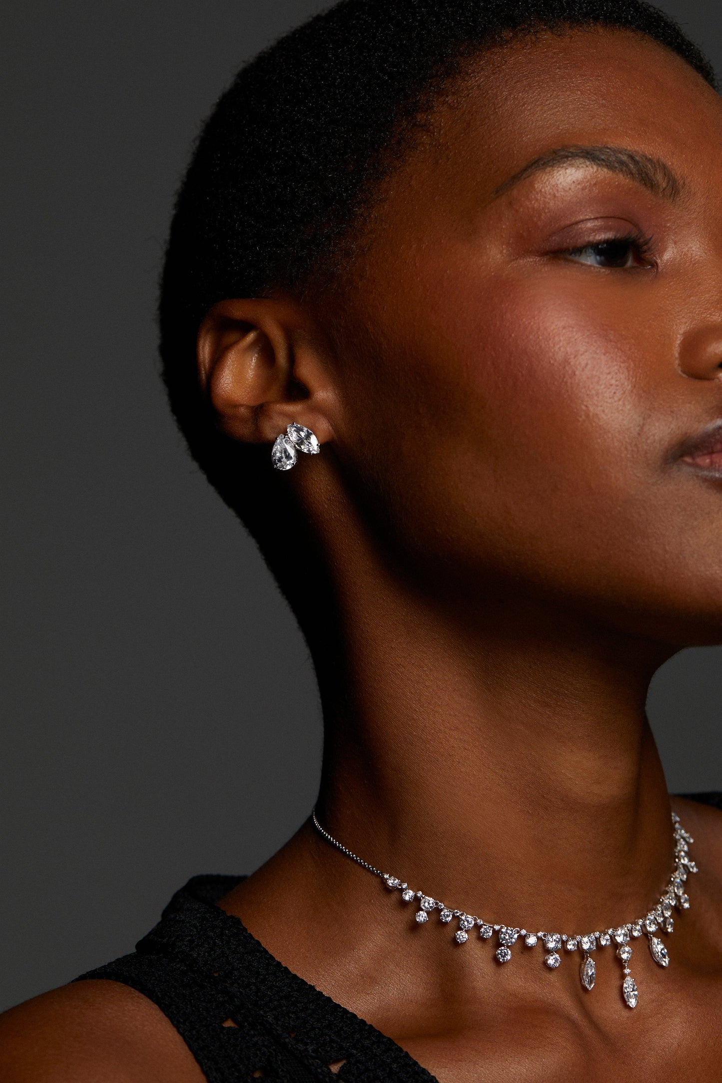 MODEL WEARING EVERLEIGH STUD EARRINGS. IT IS A CLOSE UP PROFILE IMAGE. SHE HAS ON A BLACK CROCHET TANK TOP AND WEARING A CZ COLLAR NECKLACE.