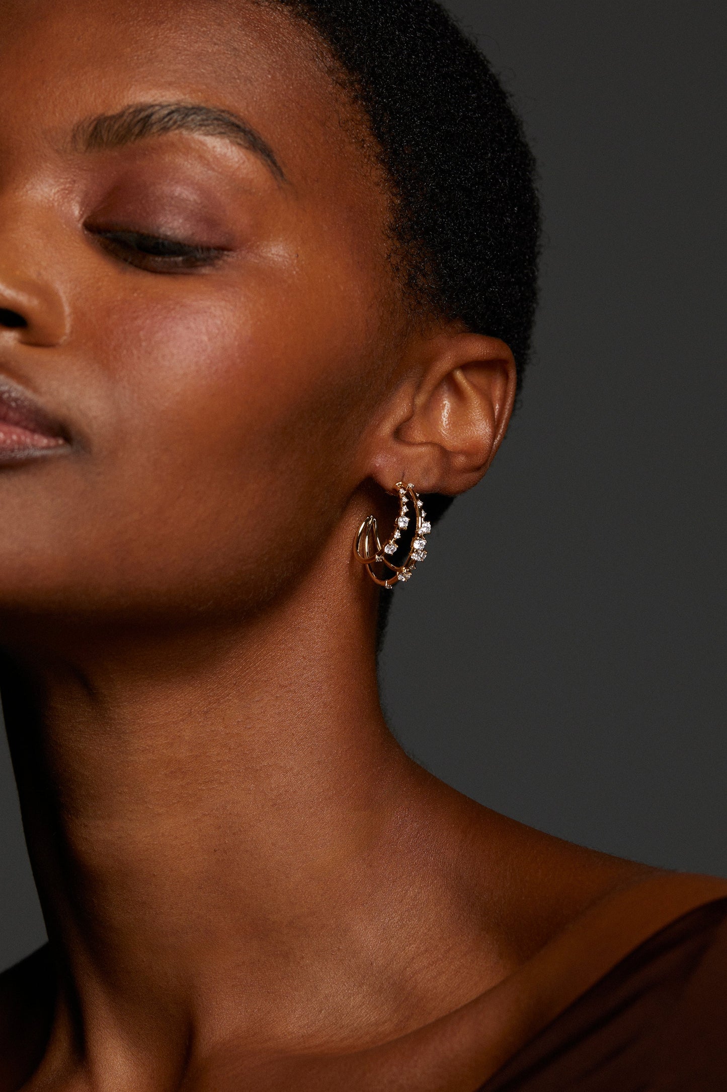 IMAGE OF MODEL WEARING EVERLEIGH MULTI C HOOP EARRINGS. HER EYES ARE CLOSED AND IT IS A TIGHT CROP FROM HER NECK UP WITH THE HOOP IN CLEAR VIEW.