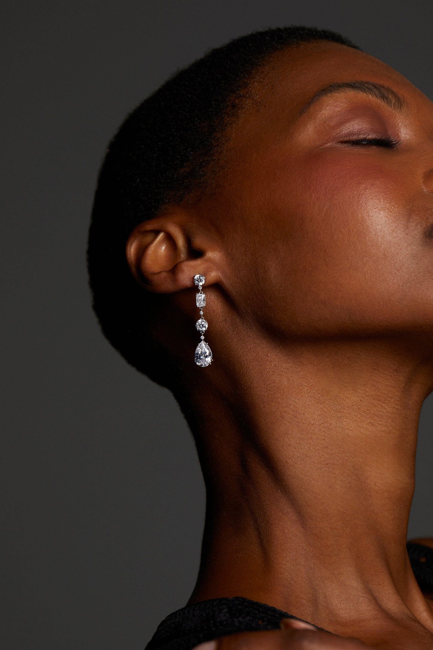 Close-up of model wearing EVERLEIGH LINEAR EARRINGS against a dark background. Her hair is buzzed so the earrings are in clear view. Her eyes are closed and it is a tight crop of her profile. 