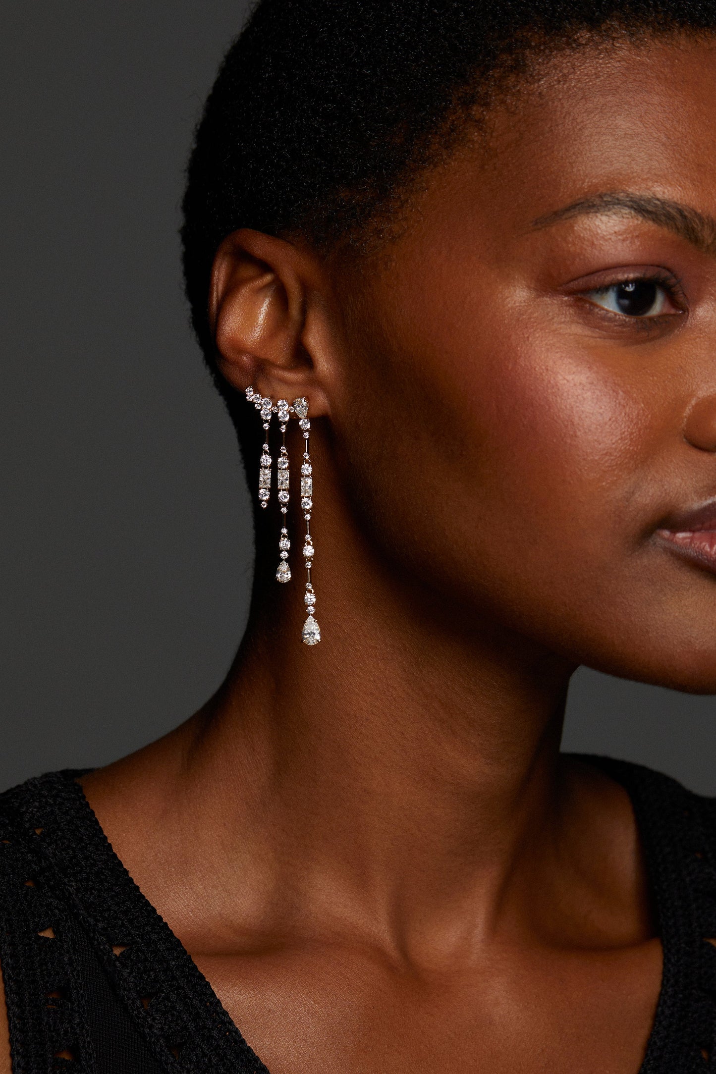 MODEL WEARING EVERLEIGH FRINGE EARRINGS. IT IS A PROFILE CLOSE UP SHOT. SHE HAS A BUZZ CUT SO THE EARRINGS ARE IN FULL VIEW AND SHE IS WEARING A BLACK CROCHET TOP.