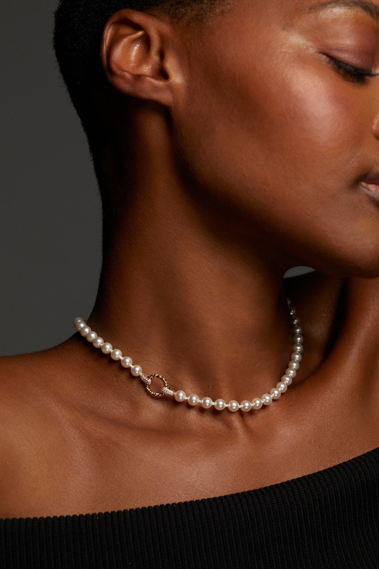 CLOSE UP IMAGE OF MODEL WEARING POPPY 6MM TWIST RING NECKLACE. HER EYES ARE CLOSED AND SHE HAS AN OFF THE SHOULDER BLACK TOP ON. 