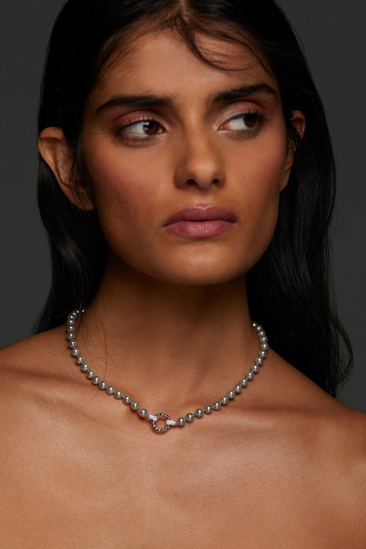 MODEL WEARING POPPY 6MM GRAY TWIST RING NECKLACE. SHE IS LOOKING OFF FRAME AND HER LONG BLACK HAIR IS BEHIND HER SHOULDERS. 