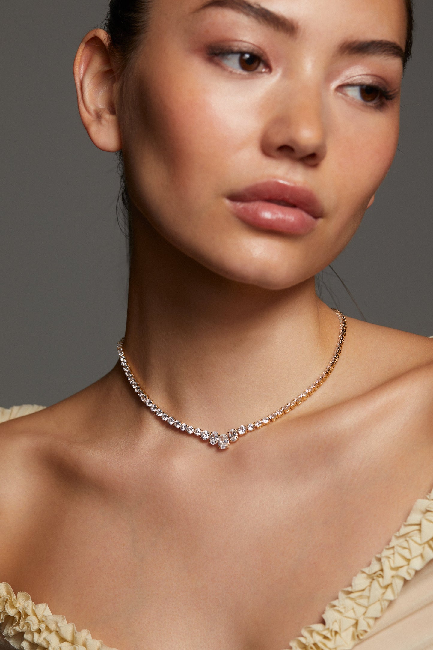 MODEL WEARING STELLAR CZ SLIDER COLLAR NECKLACE WITH AN OFF THE SHOULDER SHEER BEIGE RUFFLE TOP. 