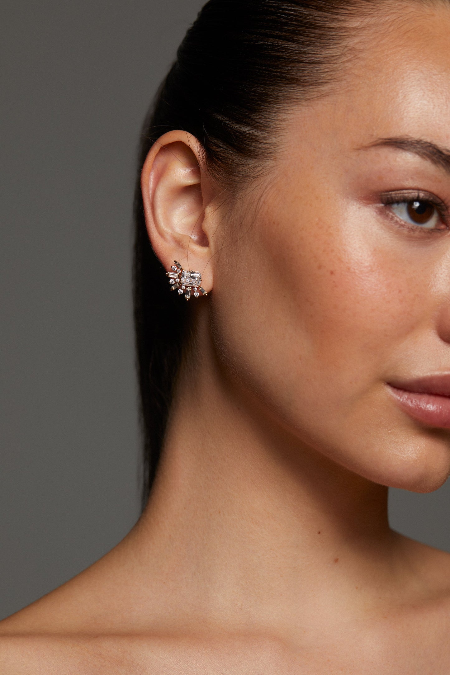 Close-up of model wearing STELLAR HALO CZ STUD EARRINGS with her hair is pulled back into a ponytail. 