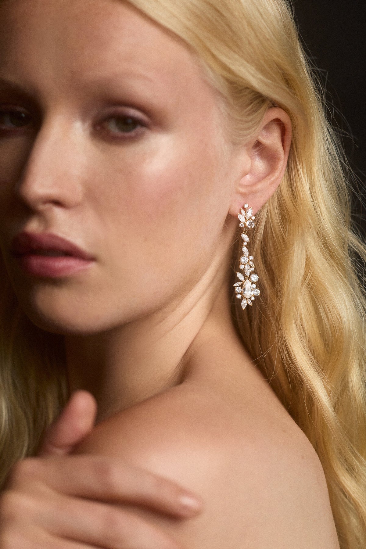 CLOSE UP OF A MODEL'S SHOULDER AS SHE TURNS TO LOOK AT THE CAMERA AND WEARS THE CANNES HOOP DROP EARRINGS