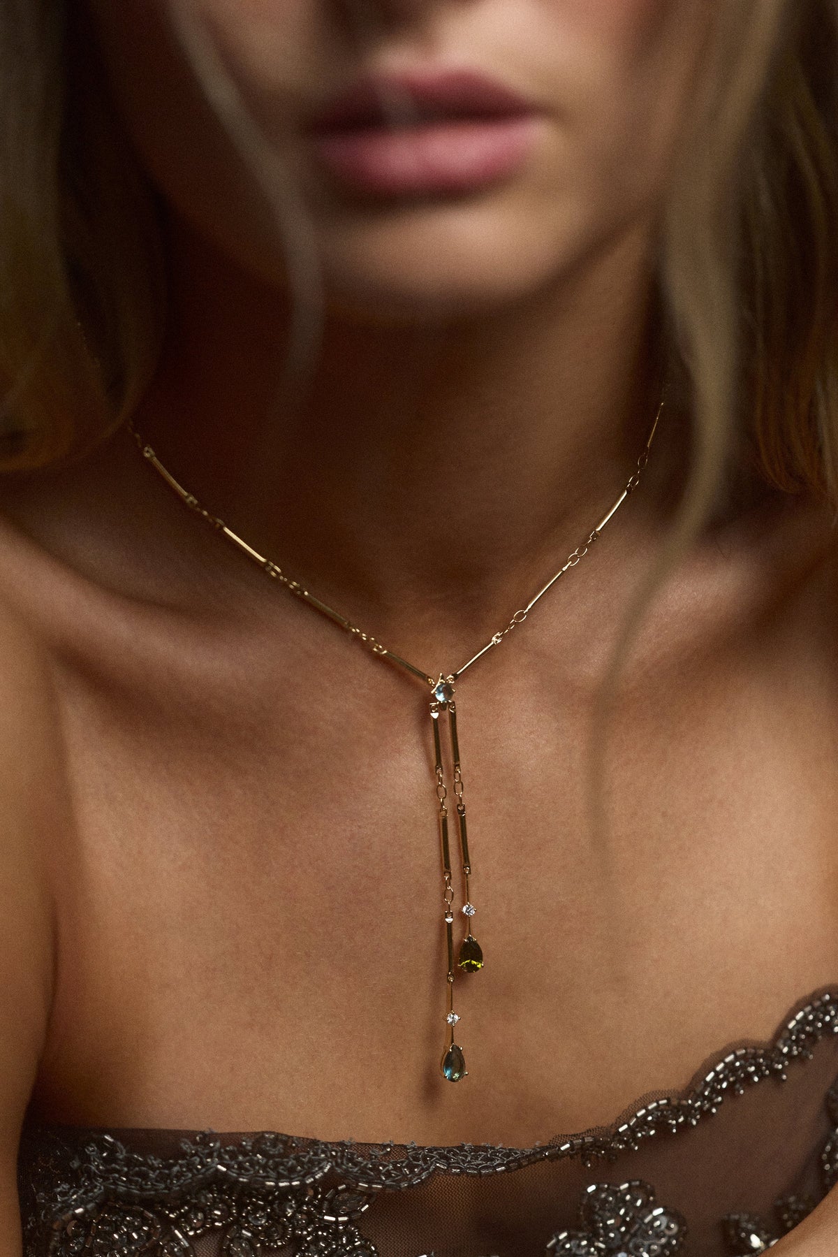 CLOSE UP OF A MODEL’S CHEST WEARING A BLACK TOP AND THE HERA MULTI FAUX LARIAT NECKLACE