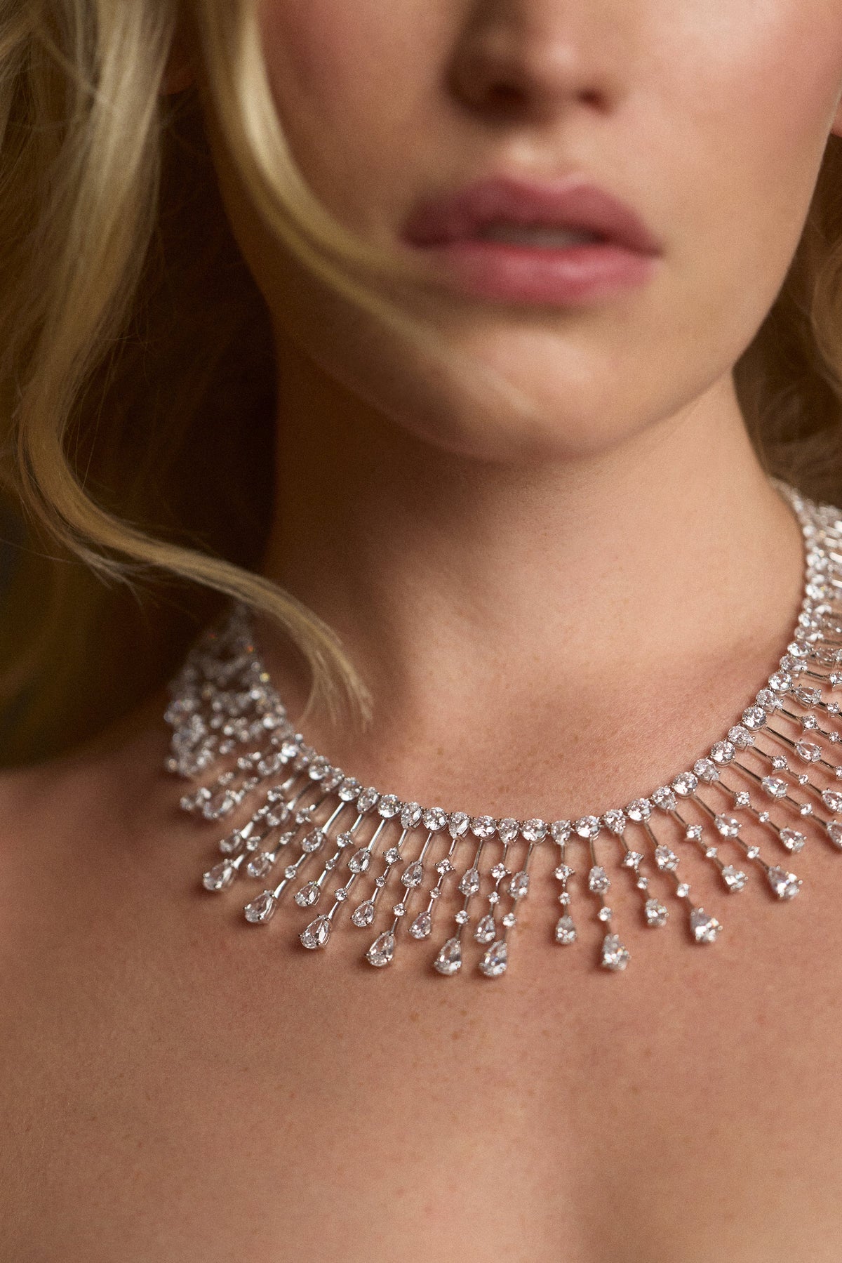 CLOSE UP OF A MODEL’S NECK WEARING THE HERA DRAMA COLLAR NECKLACE AND HER BLONDE HAIR FLOWING IN FRAME