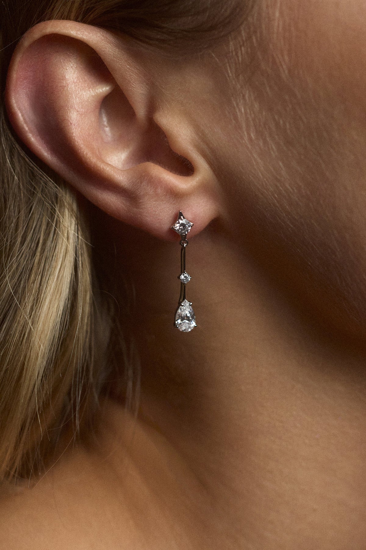 CLOSE UP OF A MODEL’S EAR WEARING THE HERA DROP EARRINGS