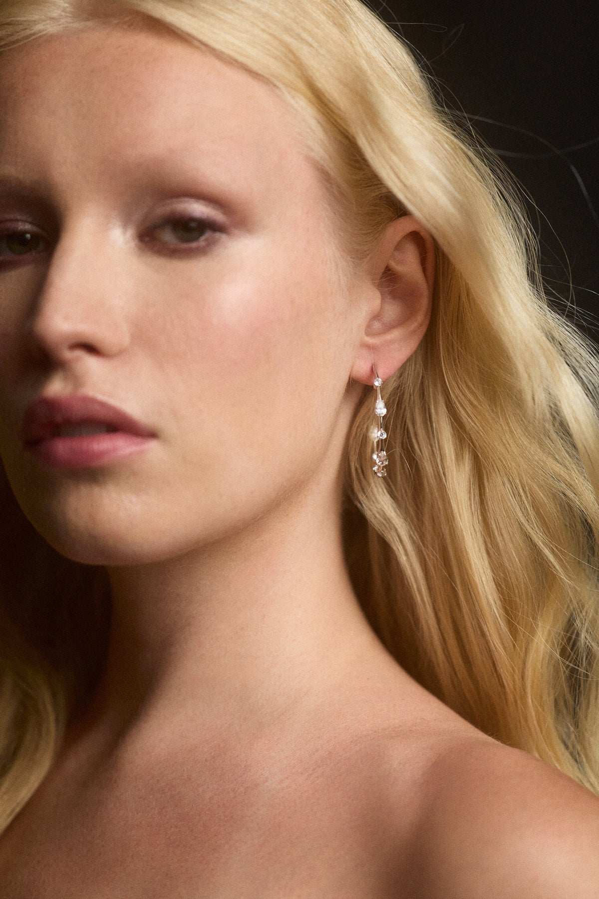 CLOSE UP OF A MODEL WITH BLONDE HAIR WEARING THE HERA ELONGATED C HOOP EARRINGS