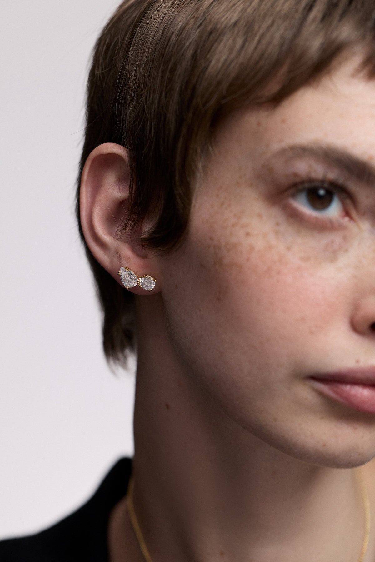 A MODEL WITH SHORT RED HAIR, WITH HALF OF HER FACE IN FRAME, AS SHE WEARS THE TWINNIE TOI MOI STUD EARRINGS