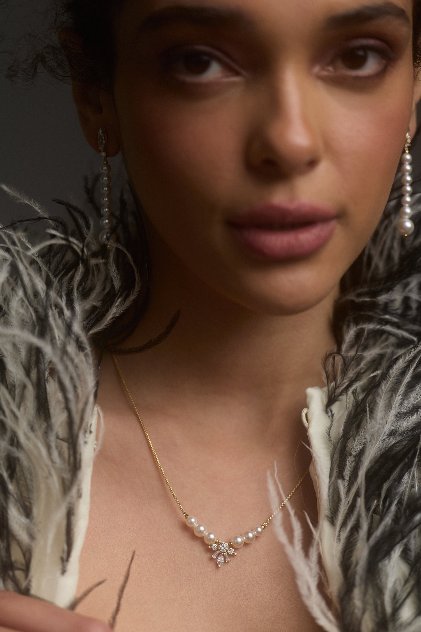 CLOSE UP OF A MODEL’S FACE AS SHE WEARS A BLACK-AND-WHITE FUR JACKET AND THE UNDER THE SEA PEARL FRONTAL NECKLACE IS IN FOCUS AROUND HER NECK
