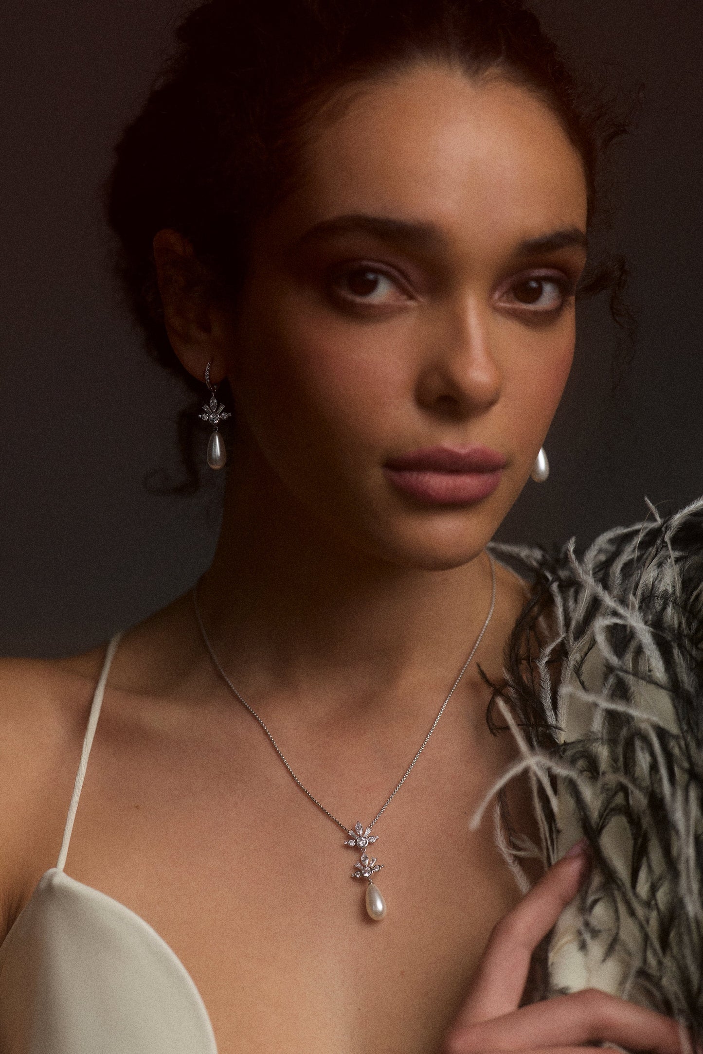 A MODEL LOOKING AT THE CAMERA AS SHE WEARS THE UNDER THE SEA TEARDROP PEARL Y NECKLACE AND THE UNDER THE SEA PEARL TEARDROP LEVERBACK EARRINGS