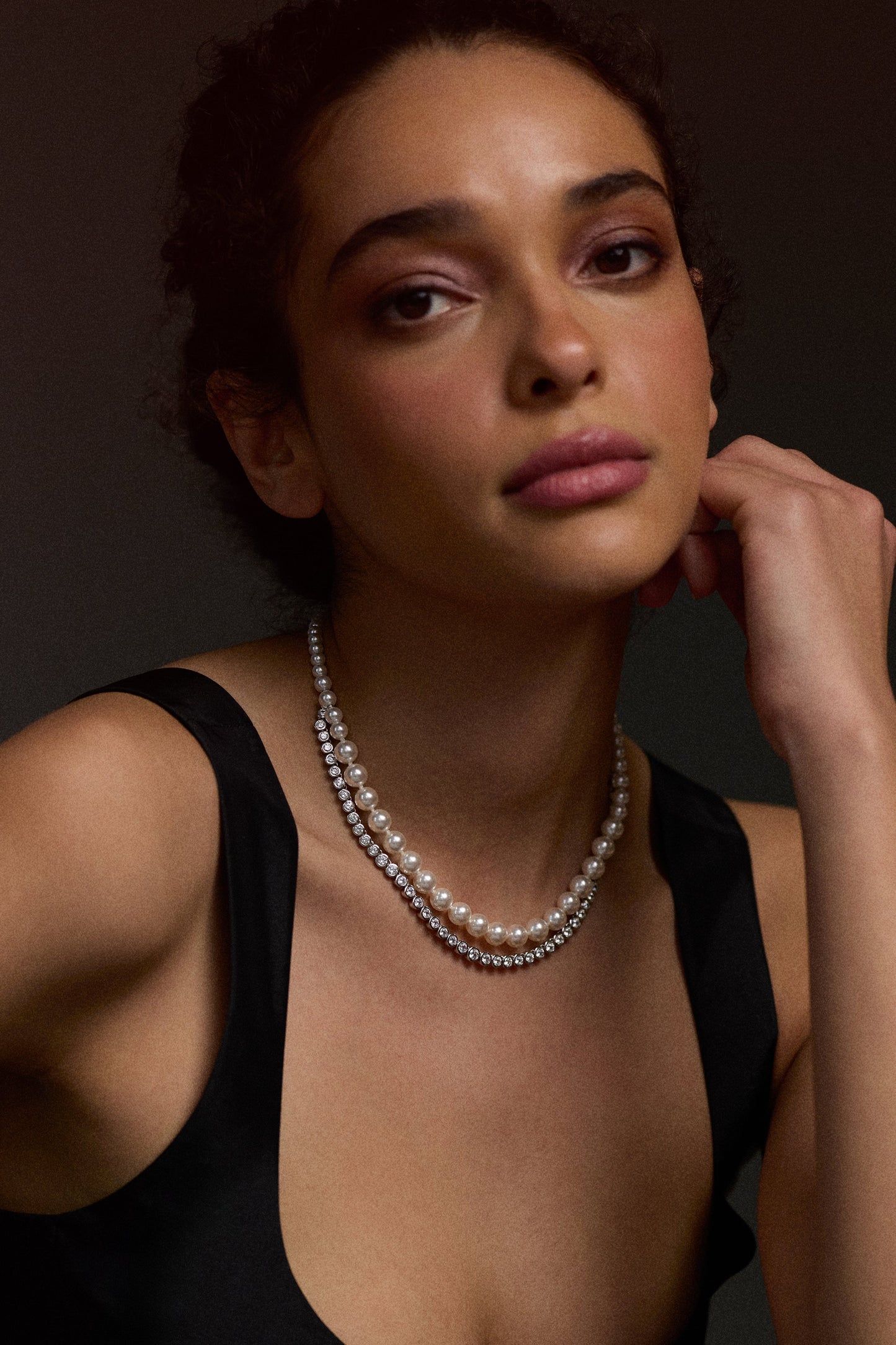 MODEL LOOKING AT THE CAMERA WITH HER HAND LIFTED UP TO HER FACE, WEARING A BLACK TOP AND THE UNDER THE SEA DOUBLE LAYER NECKLACE