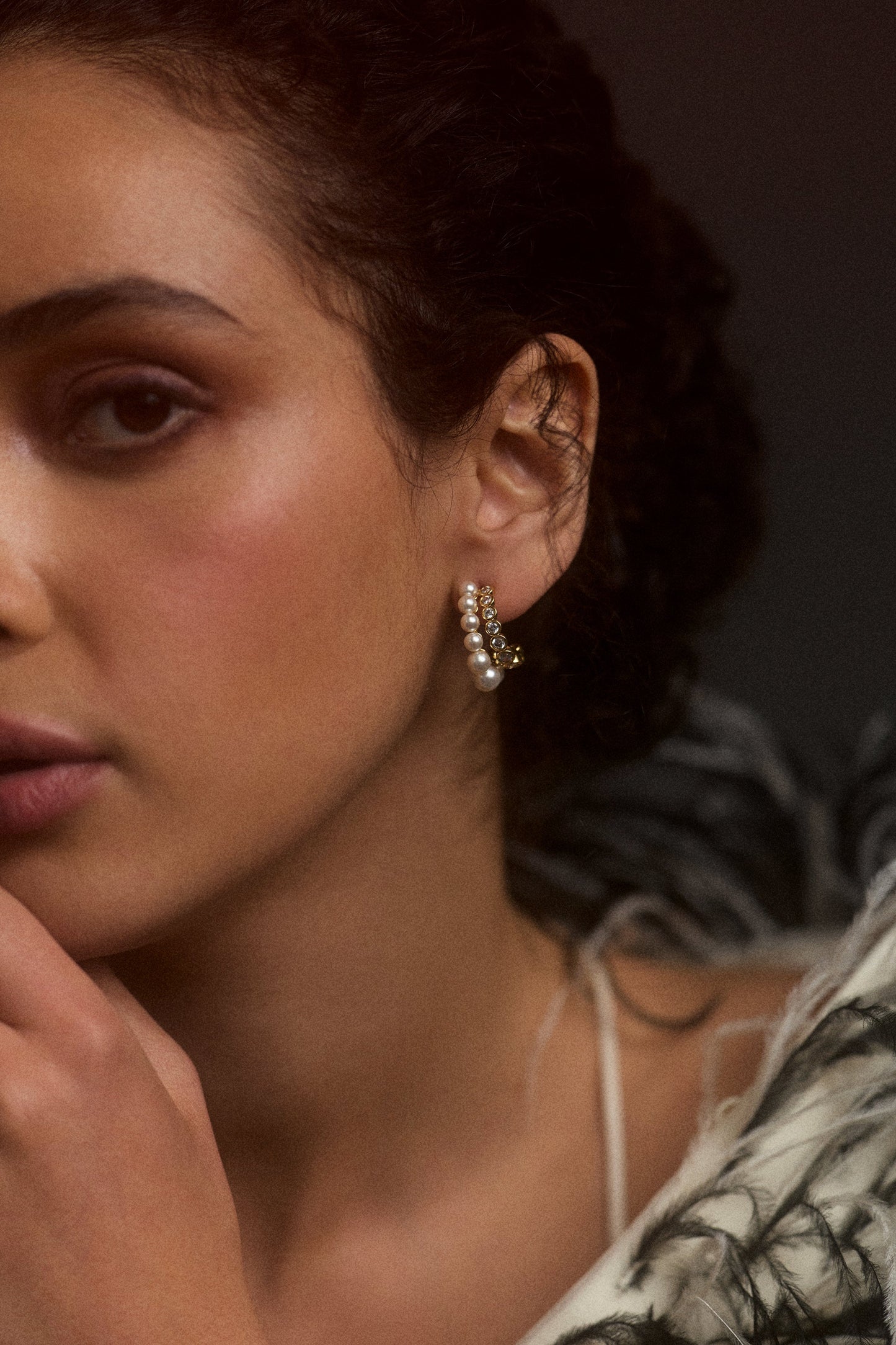 CLOSE UP OF HALF OF A MODEL’S FACE WEARING THE UNDER THE SEA DOUBLE ROW J HOOP EARRINGS, STYLED WITH A FUR JACKET