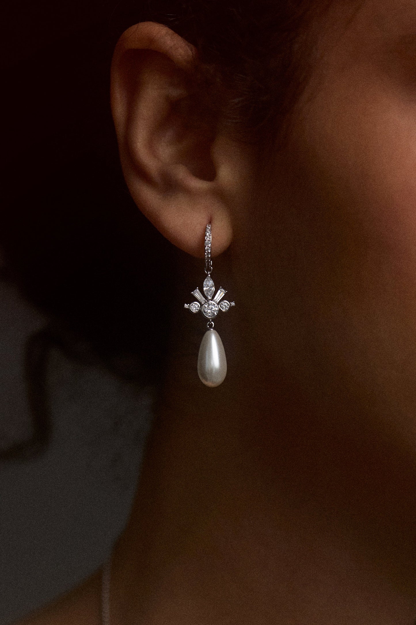 CLOSE UP OF A MODEL’S EAR WEARING THE UNDER THE SEA PEARL TEARDROP LEVERBACK EARRINGS