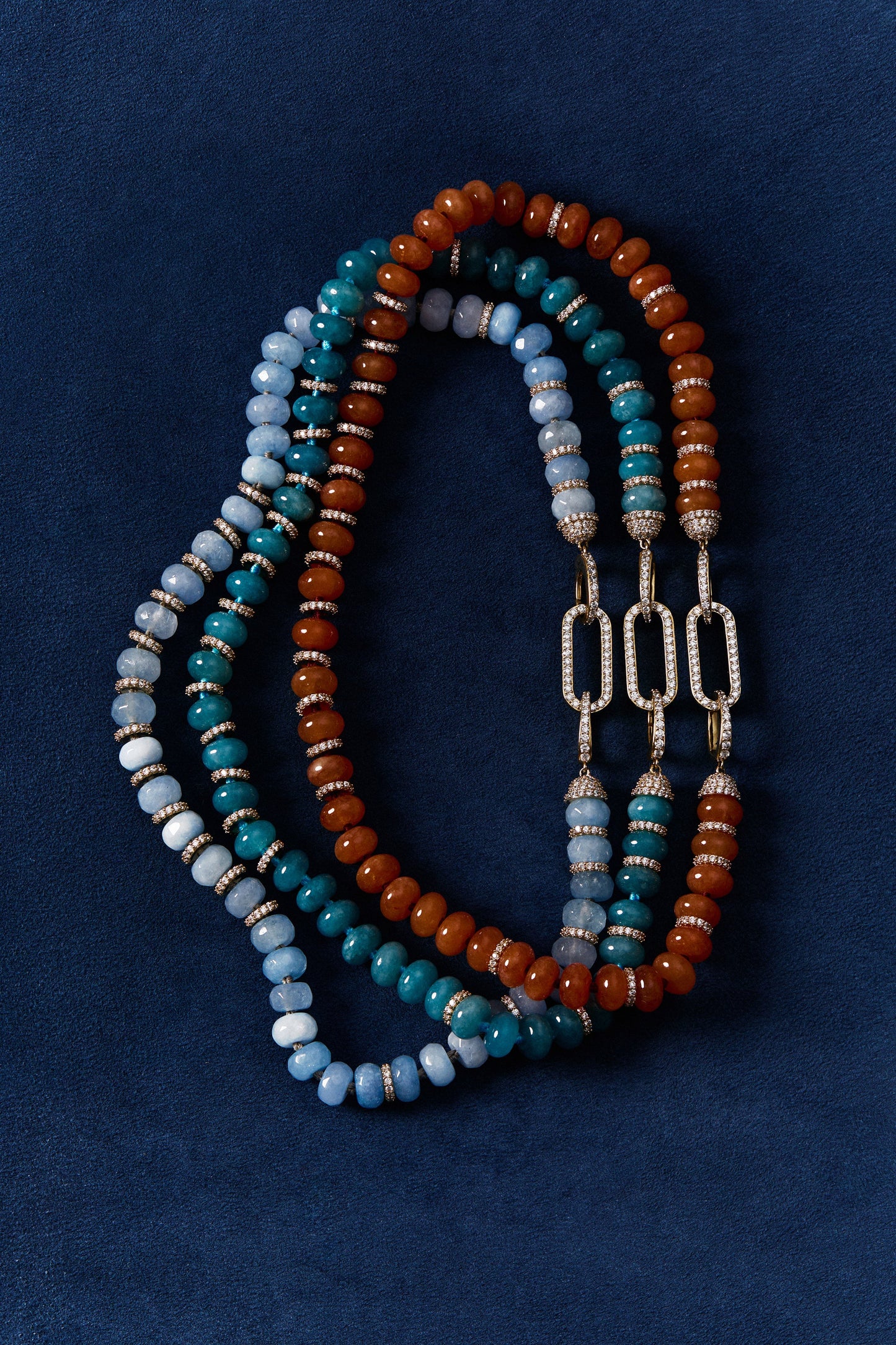 BOUJEE BEADS BLUE BRACELET, CARNELIAN BRACELET, AND LIGHT BLUE BRACELET LAID OUT AGAINST A BLUE BACKGROUND