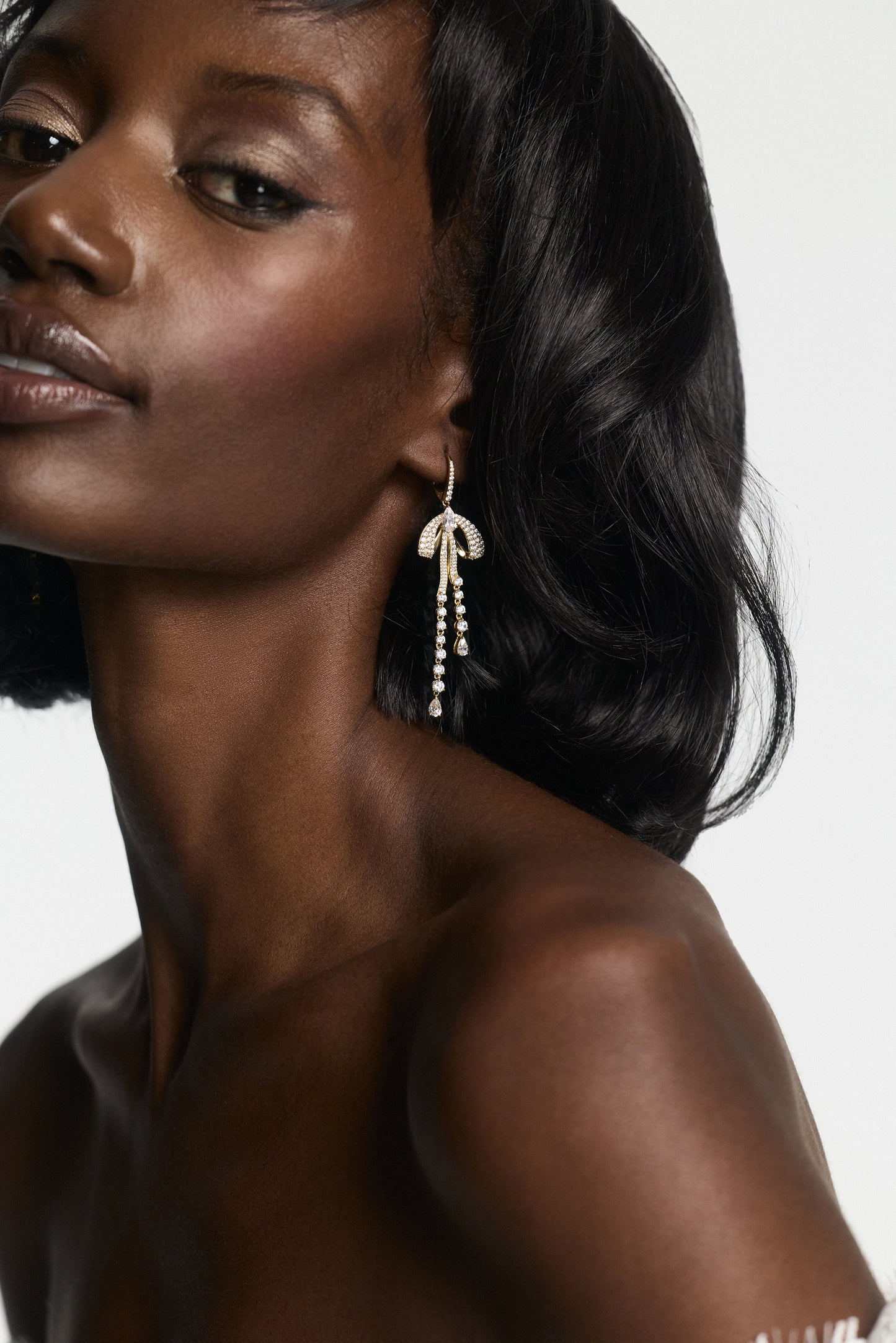 SIDE PROFILE OF A MODEL WEARING EROS PAVÉ BOW LEVERBACK EARRINGS, WITH HER HEAD TILTED UPWARD