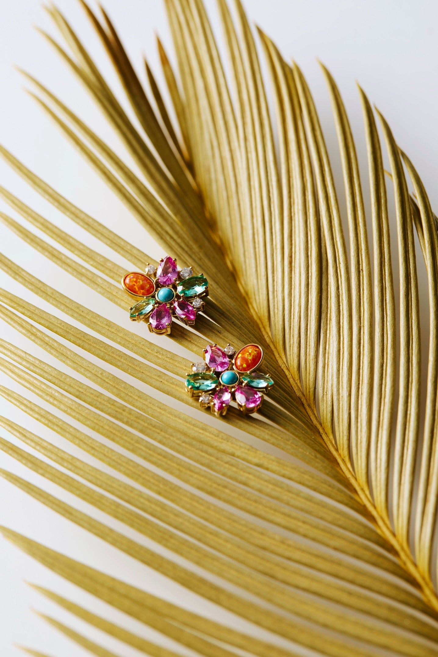 FRIEDA FLORAL STUDS EARRINGS ON A LARGE GREEN LEAF