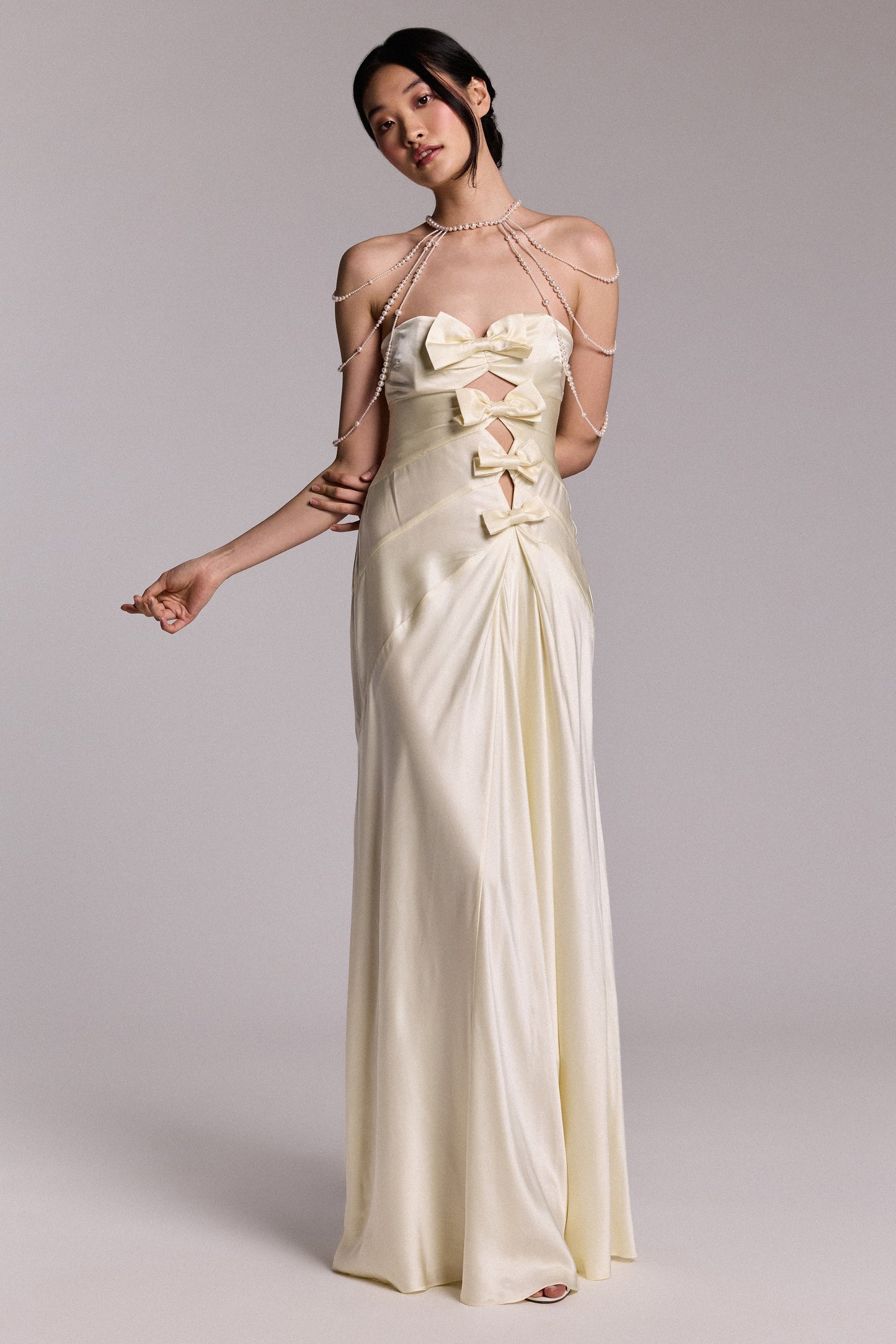 MODEL POSING IN A WEDDING DRESS WITH BOW DETAILING, STYLED WITH THE PEARL CHOKER SHOULDER SWAG NECKLACE
