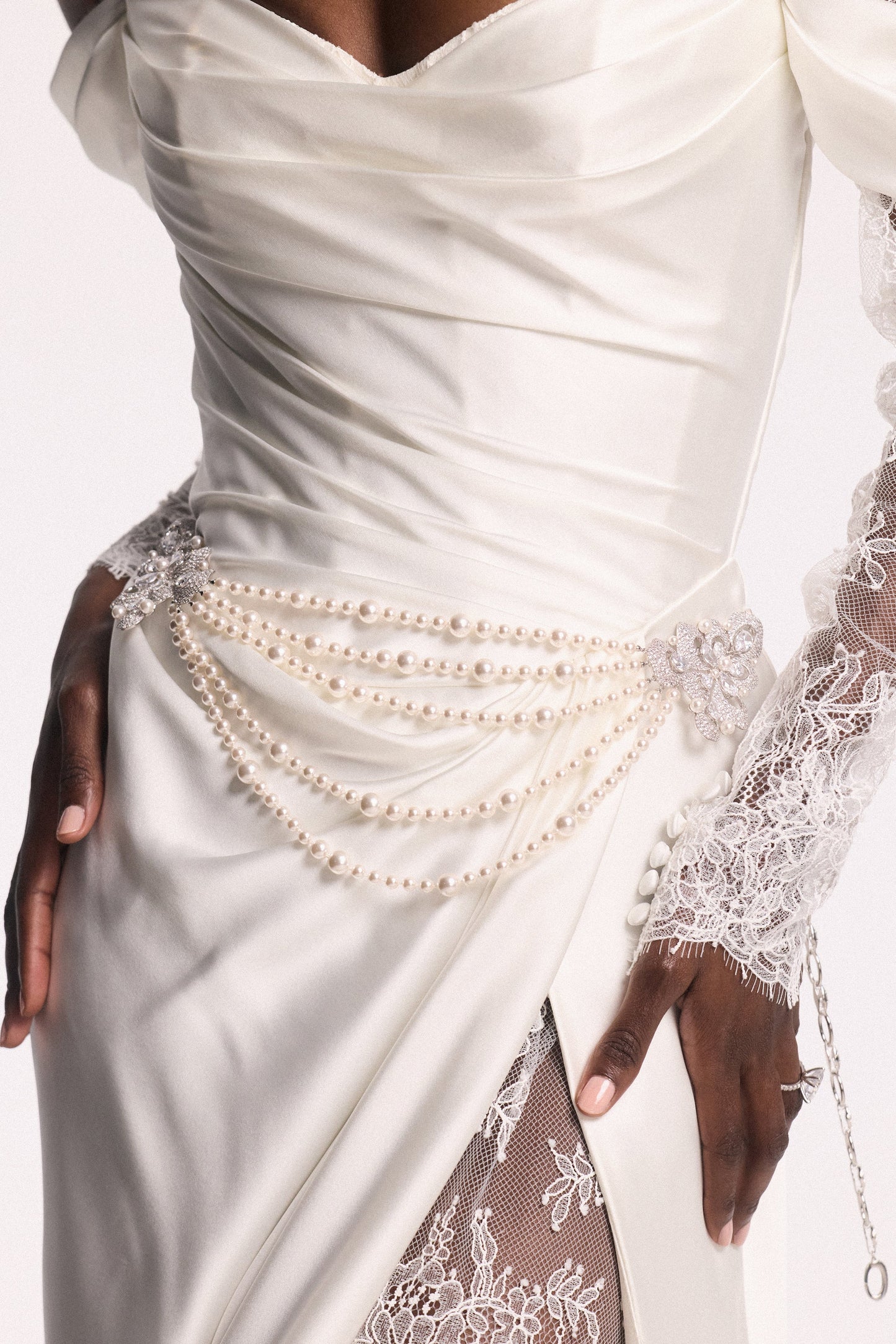 CLOSE UP OF A MODEL’S WAIST WEARING A WHITE WEDDING GOWN AND THE PEARL SWAG BROOCH BELT