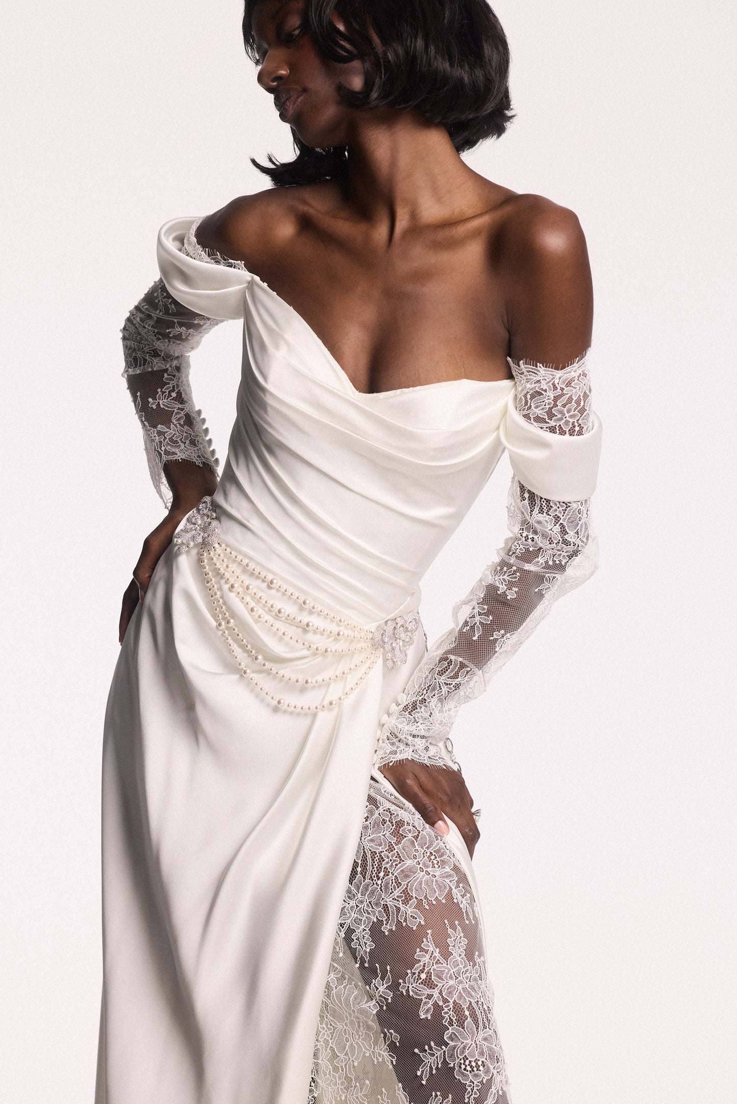 A MODEL POSING IN A WHITE WEDDING GOWN AND THE PEARL SWAG BROOCH BELT