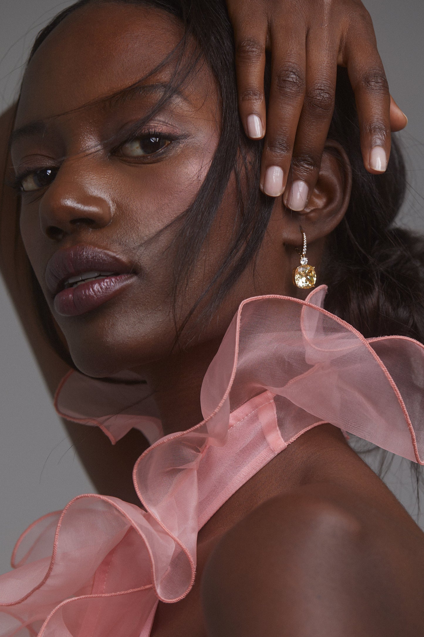 MACARON YELLOW DROP EARRINGS ON MODEL. SHE IS FACING THE CAMERA HOLDING HER HAIR BACK AWAY FROM EARS WEARING A PINK RUFFLE TOP. 