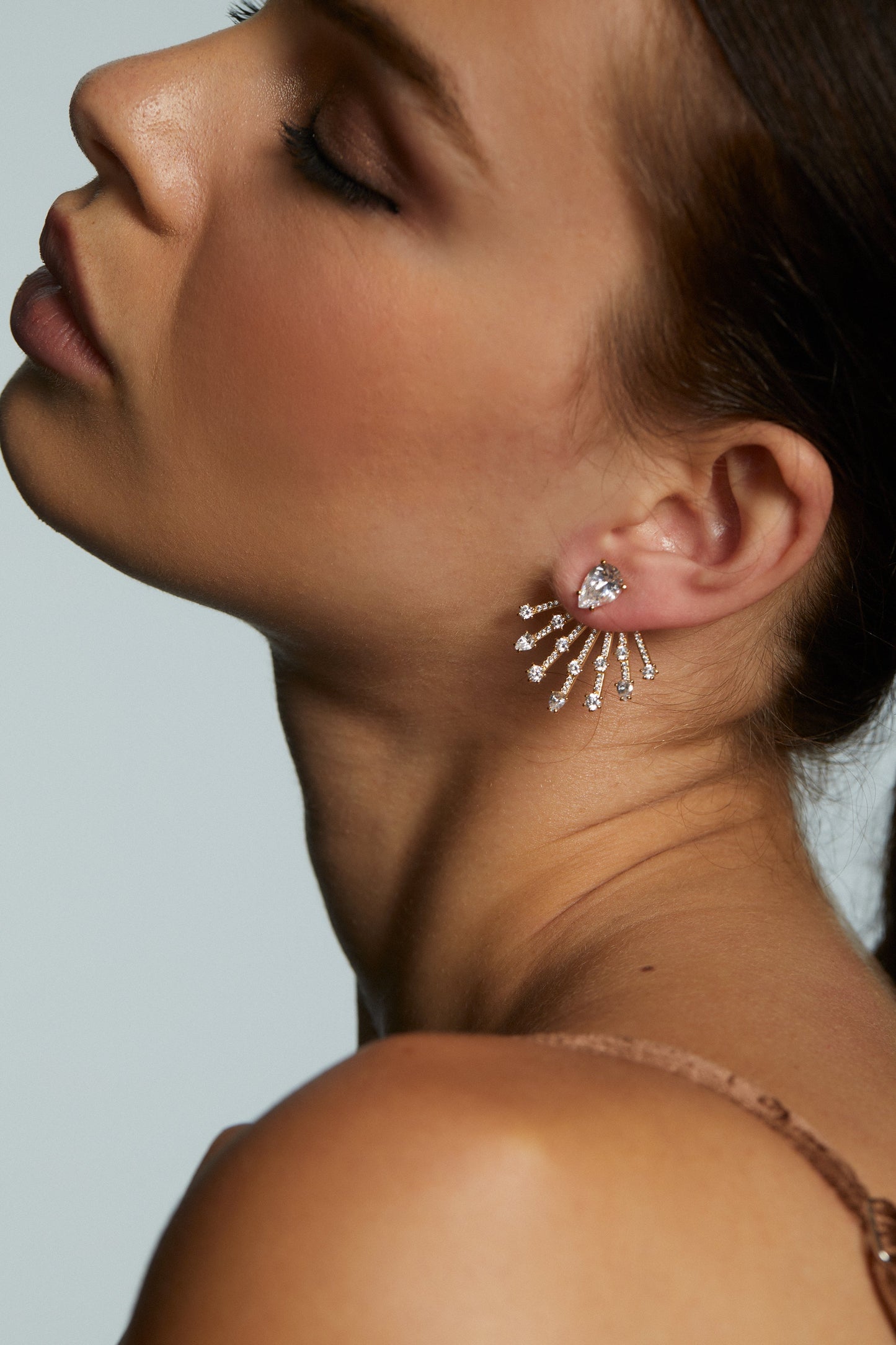 Close-up of a woman wearing sparkling earrings against a neutral background