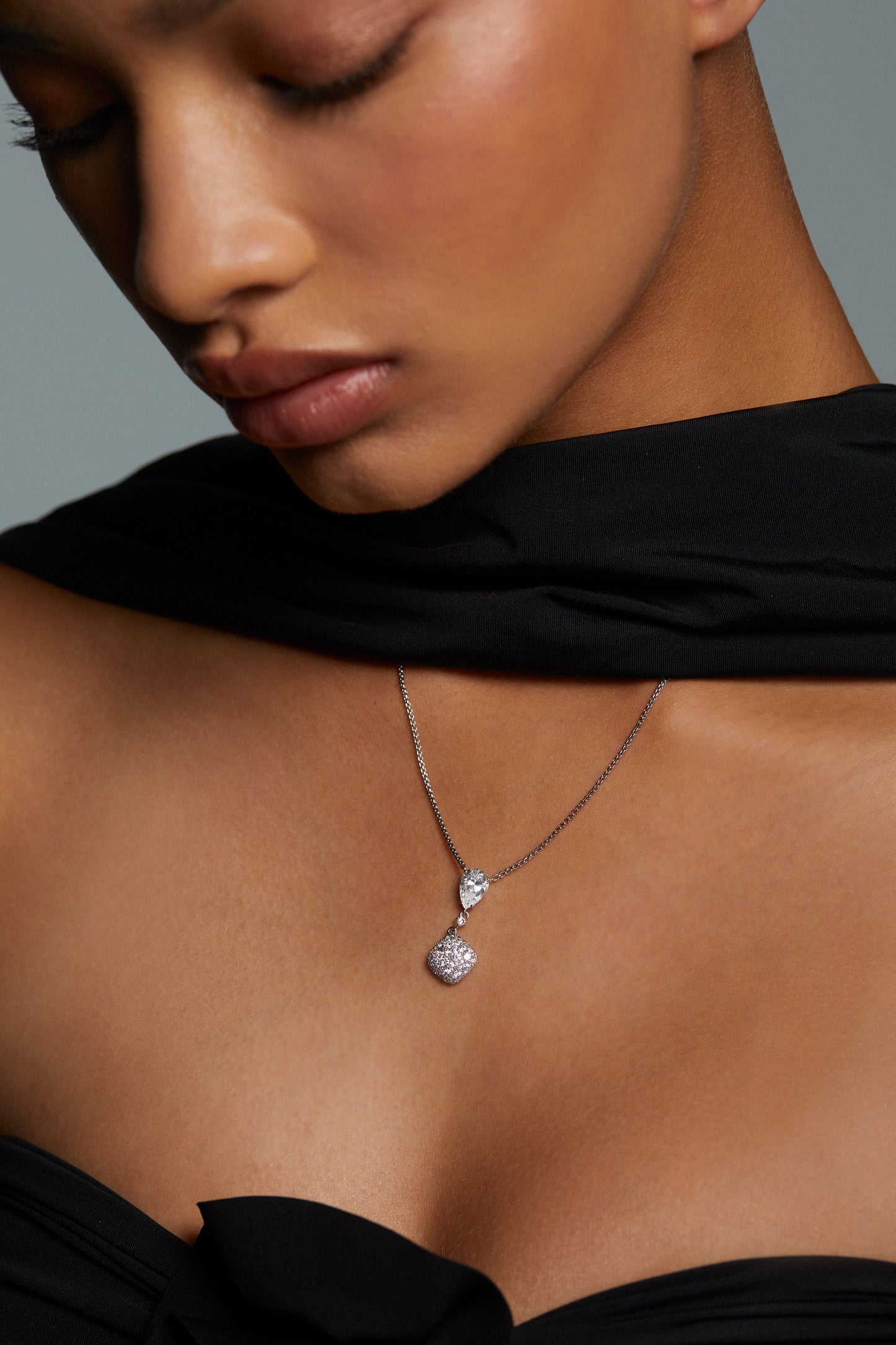 CLOSE UP IMAGE OF MODEL WEARING CRUSHED PAVE CUSHION DROP NECKLACE. SHE HAS ON A BLACK STRAPLESS DRESS AND MATCHING SCARF.