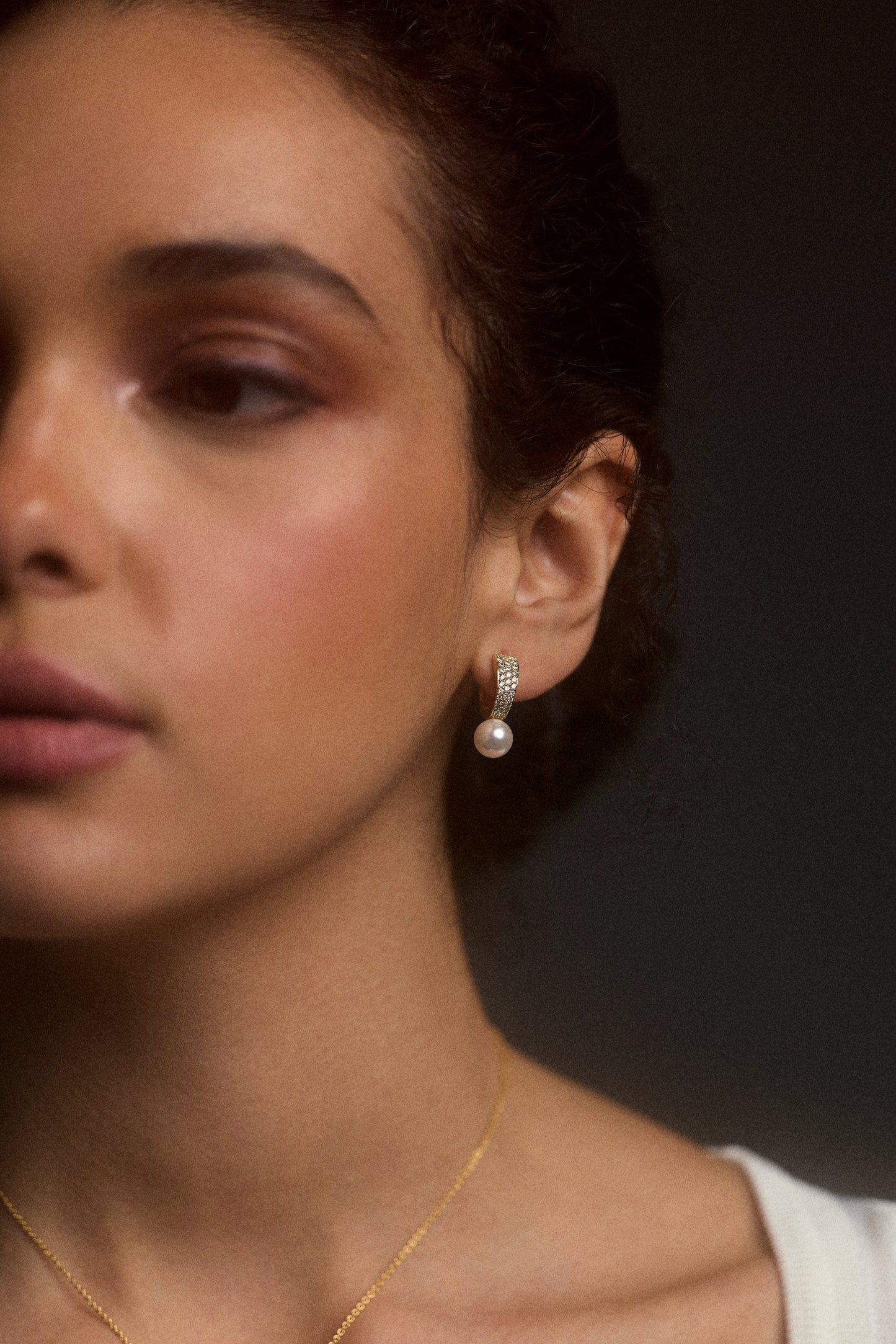 CLOSE UP OF HALF OF A MODEL’S FACE WEARING THE UNDER THE SEA PEARL HUGGIE EARRINGS
