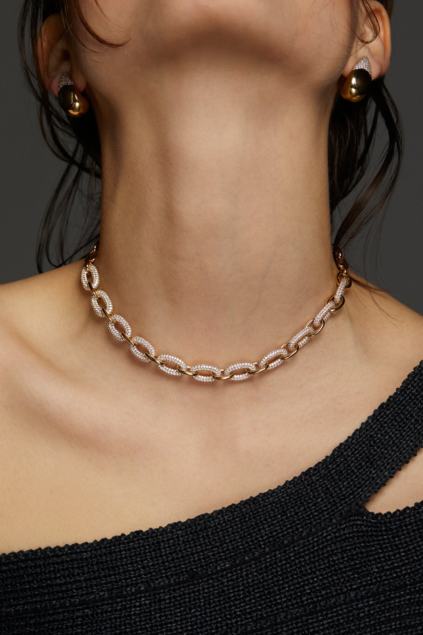 MODEL WEARING ALMA DRAMA PAVE LINK NECKLACE. IT IS A CLOSE UP IMAGE OF HER NECK SHOWING THE PAVE CZ DETAIL. SHE IS WEARING A BLACK ONE SHOULDER TOP.