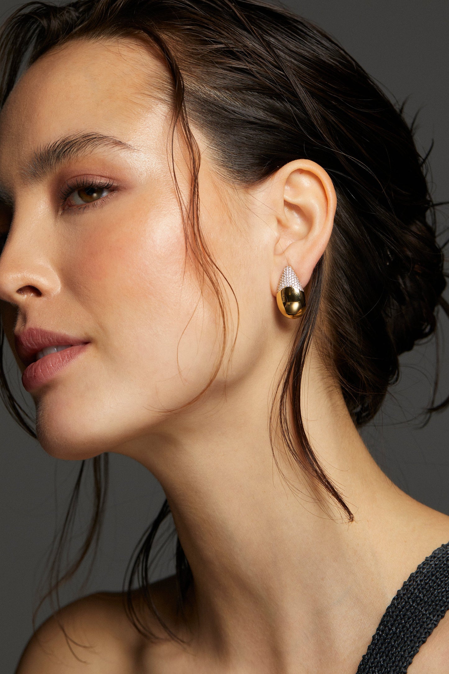 MODEL WEARING ALMA TEARDROP EARRINGS. IT IS A CLOSE UP IMAGE SHE IS FACING SIDEWAYS WITH HER BROWN HAIR PULLED BACK IN A LOOSE BUN. 