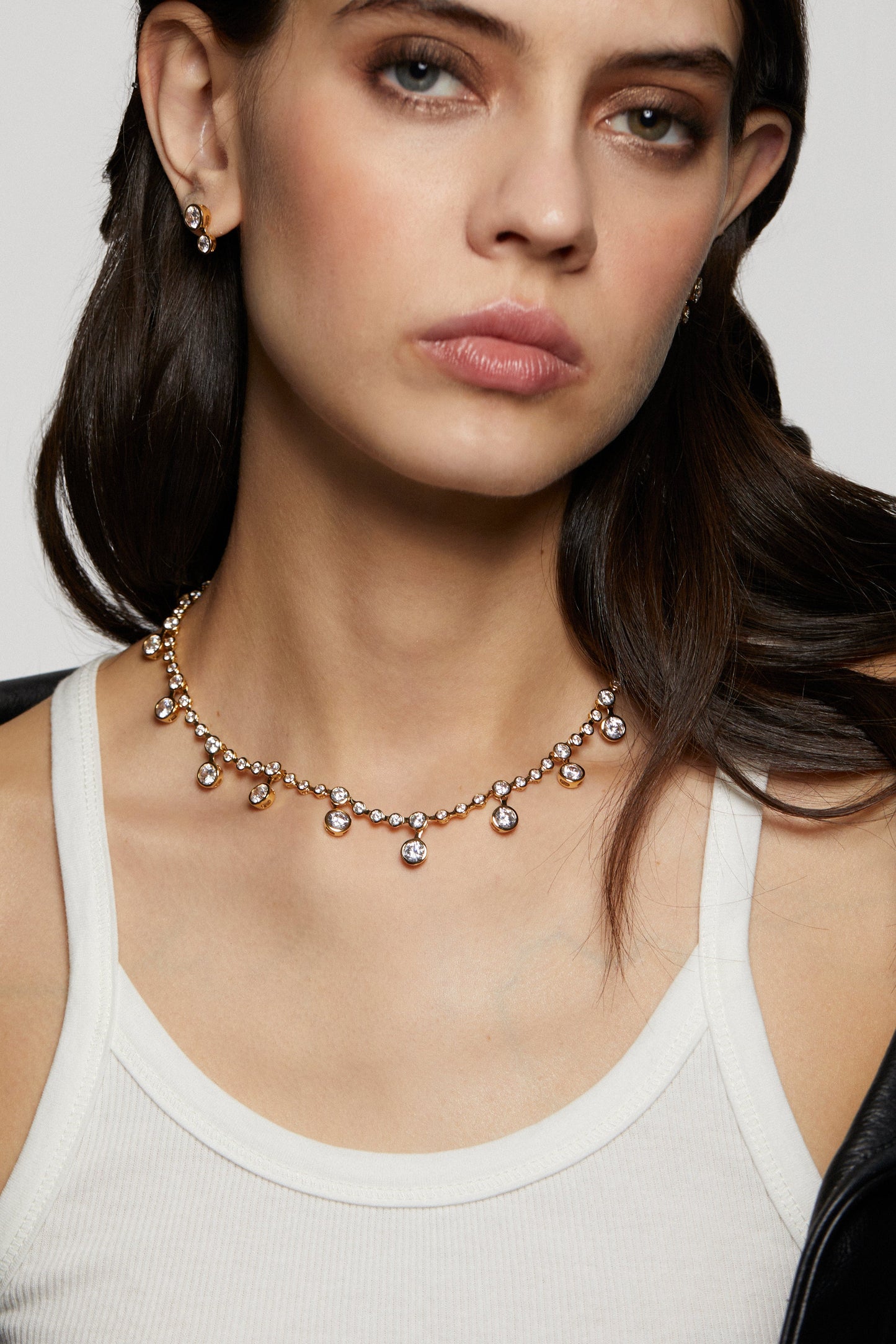 Woman wearing a delicate necklace with a plain background