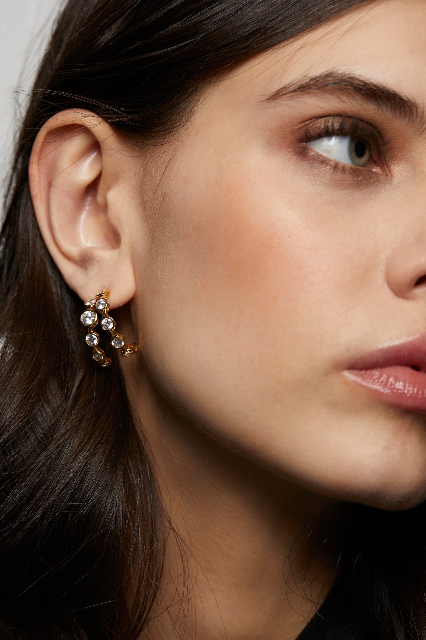 CLOSE UP OF MODEL WEARING BROOKLYN DOUBLE ROW C HOOP EARRINGS. HER HAIR IS BEHIND HER EAR TO THE HOOP IS IN FULL VIEW. 
