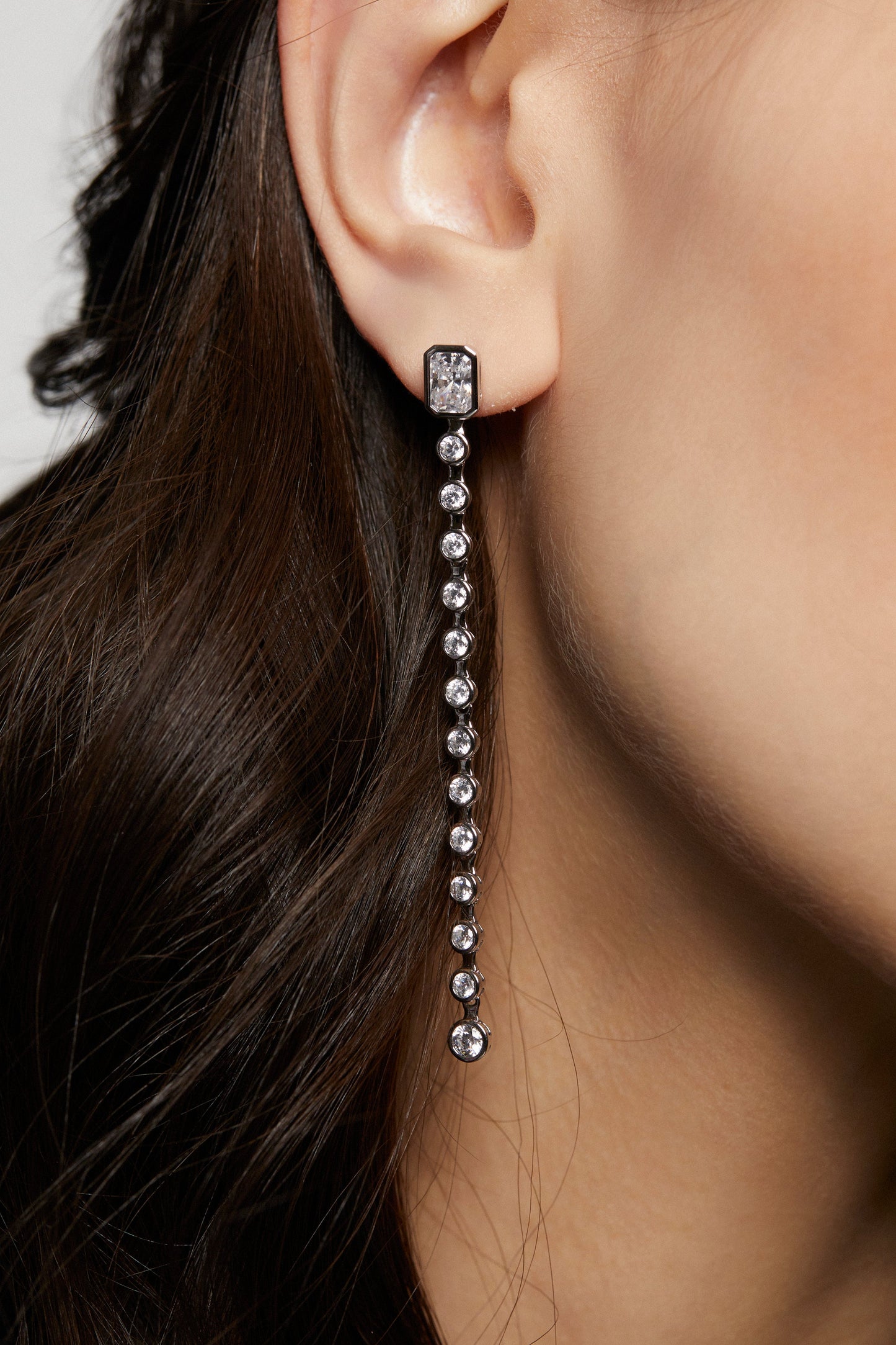 MODEL WEARING BROOKLYN LONG LINEAR EARRINGS. IT IS A CLOSE UP IMAGE OF HER EARS SHOWING THE DETAIL OF THE EARRINGS.