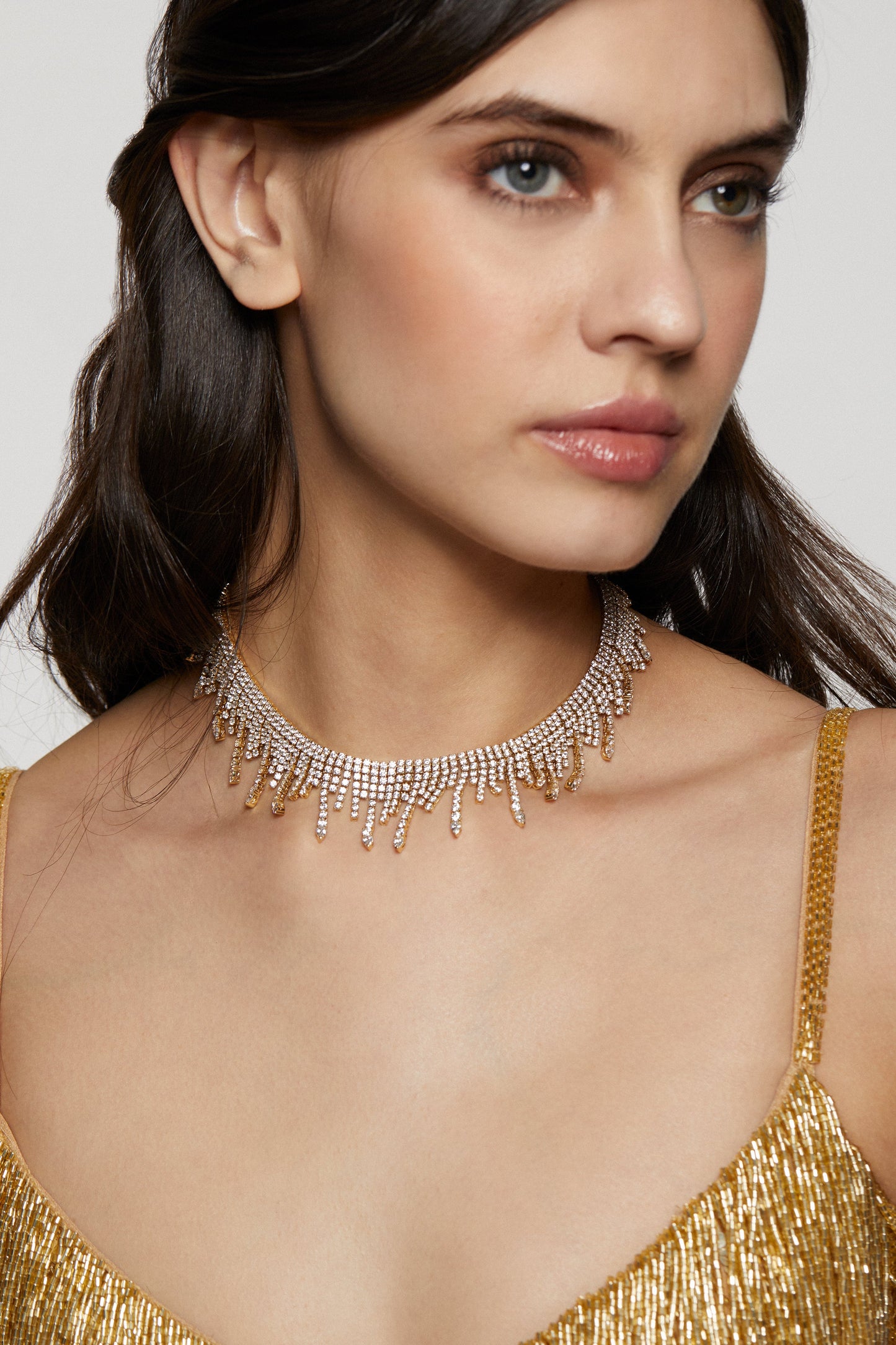 MODEL WEARING DIVA FRINGE CHOKER NECKLACE. HER HAIR IS PULLED BACK AND SHE IS WEARING A SHIMMERING BEADED GOLD DRESS. 