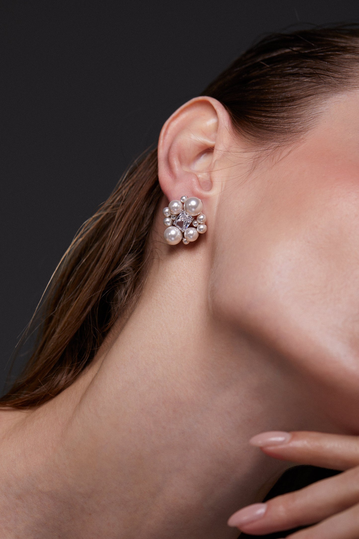 INGRID PEARL CLUSTER STUD EARRINGS ON MODEL. IT IS A CLOSE UP IMAGE OF HER EAR WITH HER HAIR SLICKED BACK.